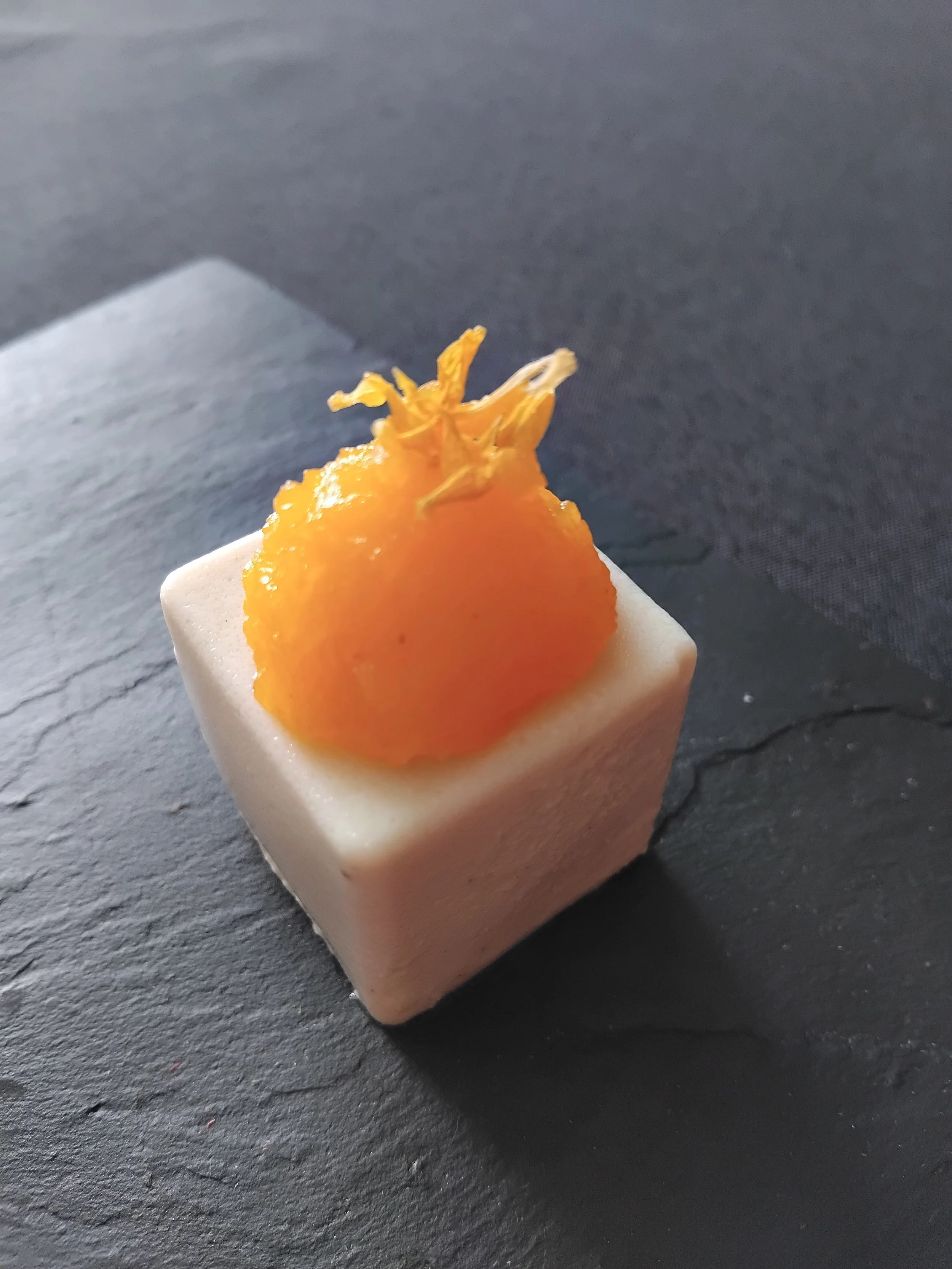 VECETO: Tactile materiality, cauliflower cube and apricot on slate. Black garlic hidden inside, found only by touch.
