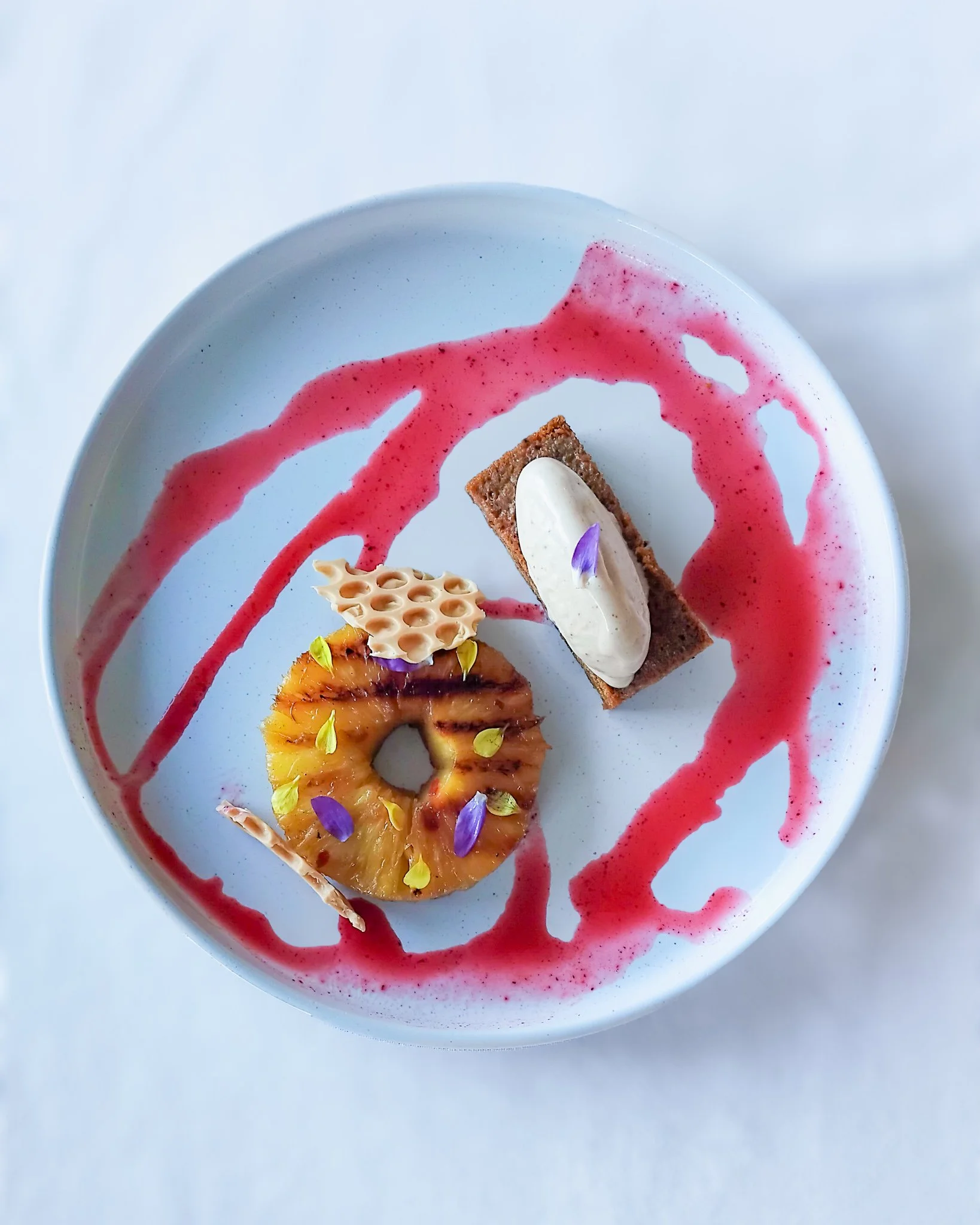 Grilled Pineapple, cake and ice over abstract plated sauce