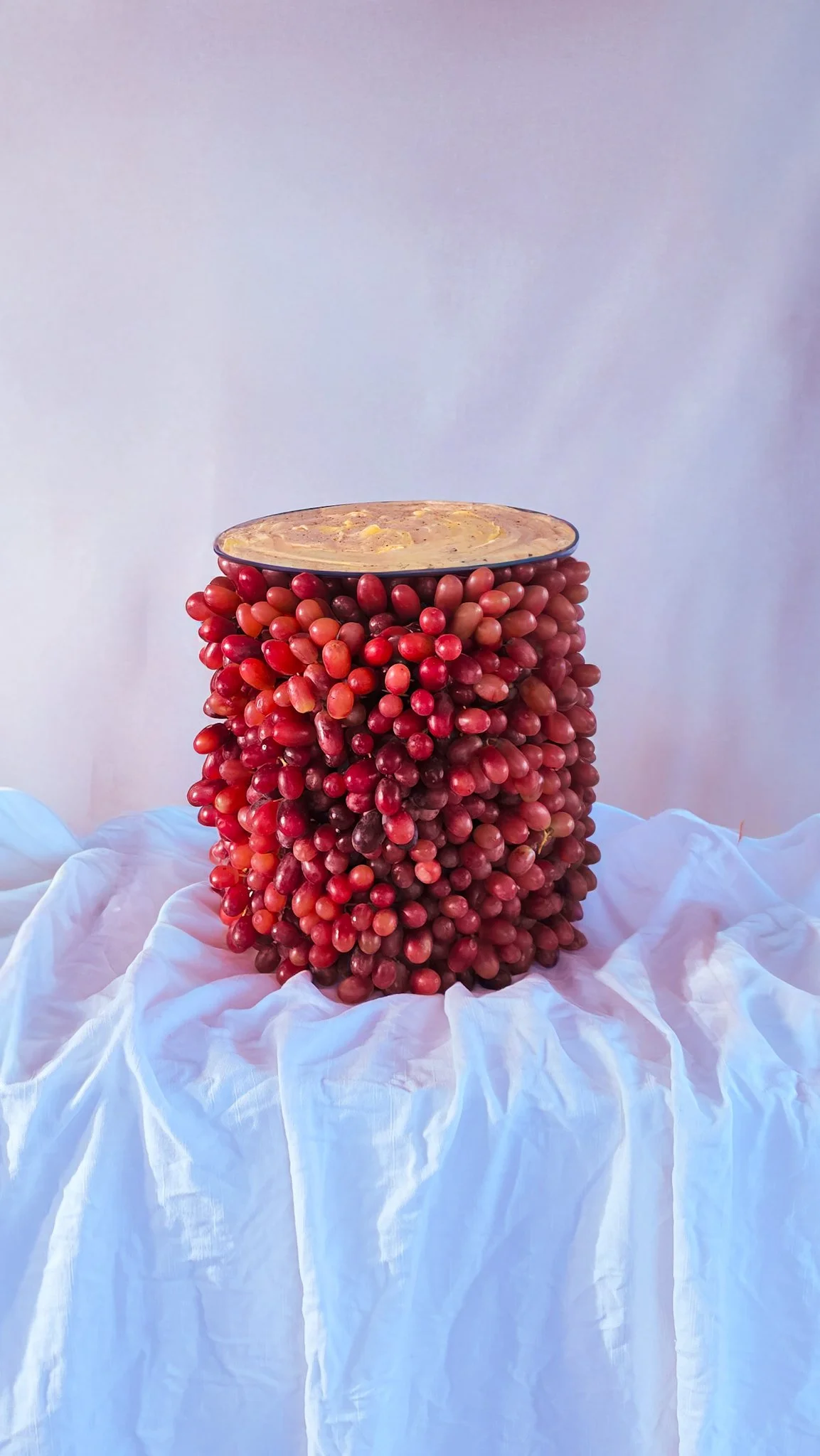 VECETO: Pink grapes stacked to a grey bowl of gratin beside Apollo. Food sculpture artists, tactile materiality.