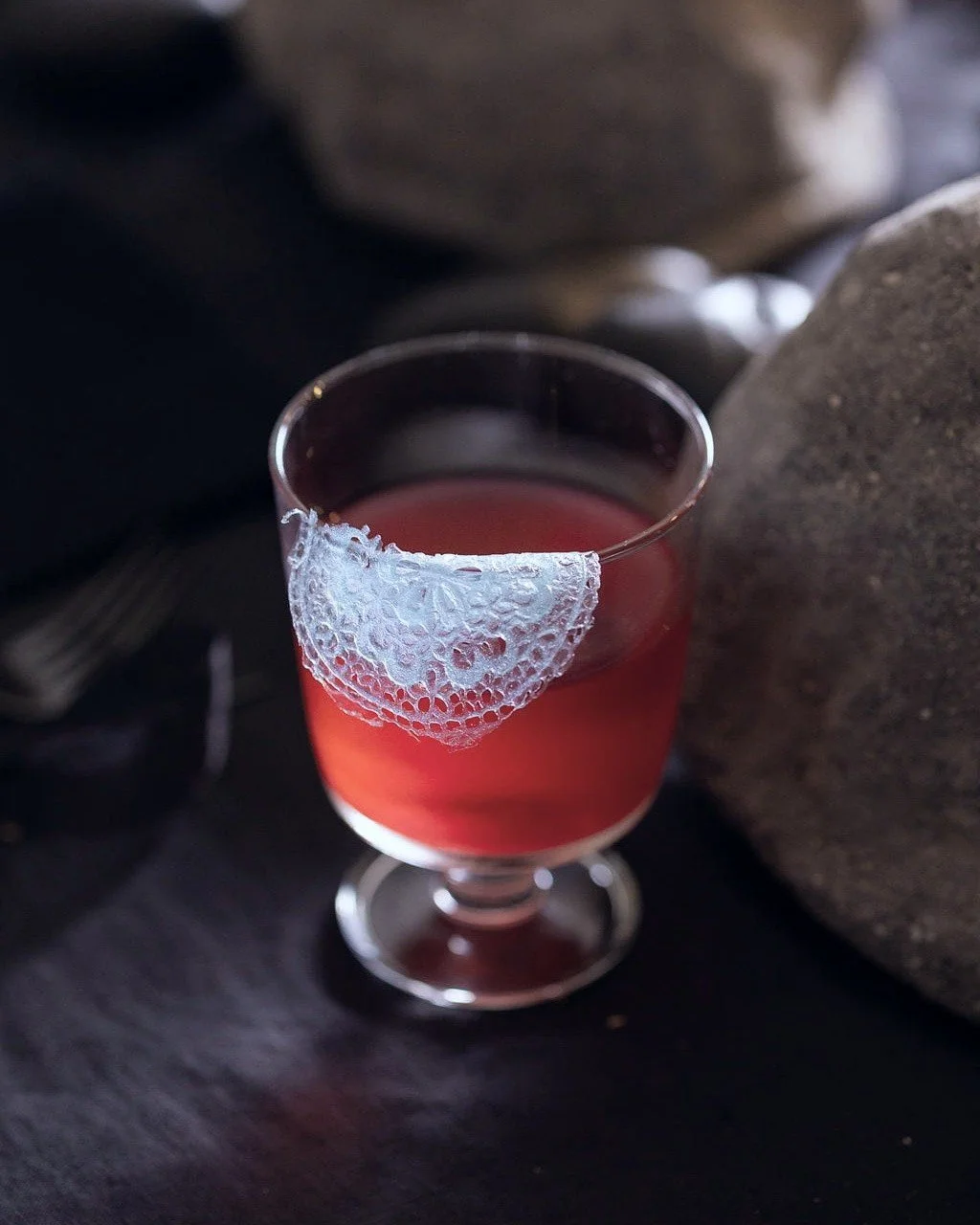 VECETO: Edible lace, red elixir. Blue lace at the rim of the glass, concrete behind.
