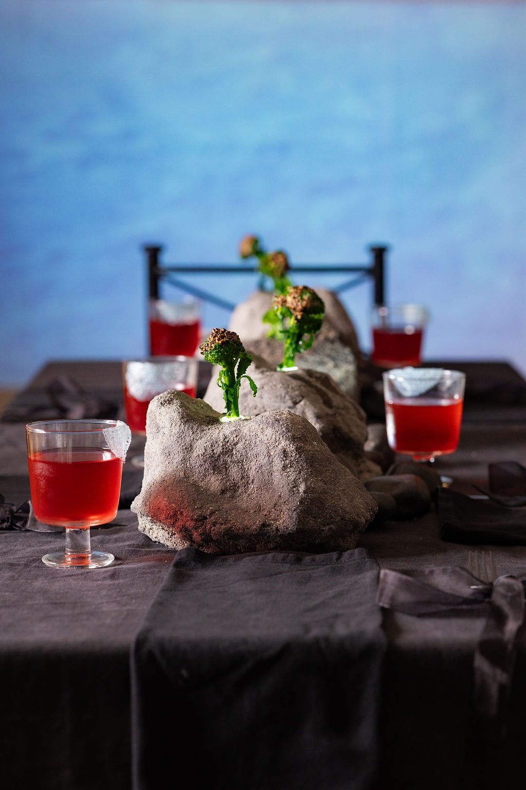 Immersive installation art by Veceto: hand-crafted stone vessels with broccolini, set against an ocean projection.