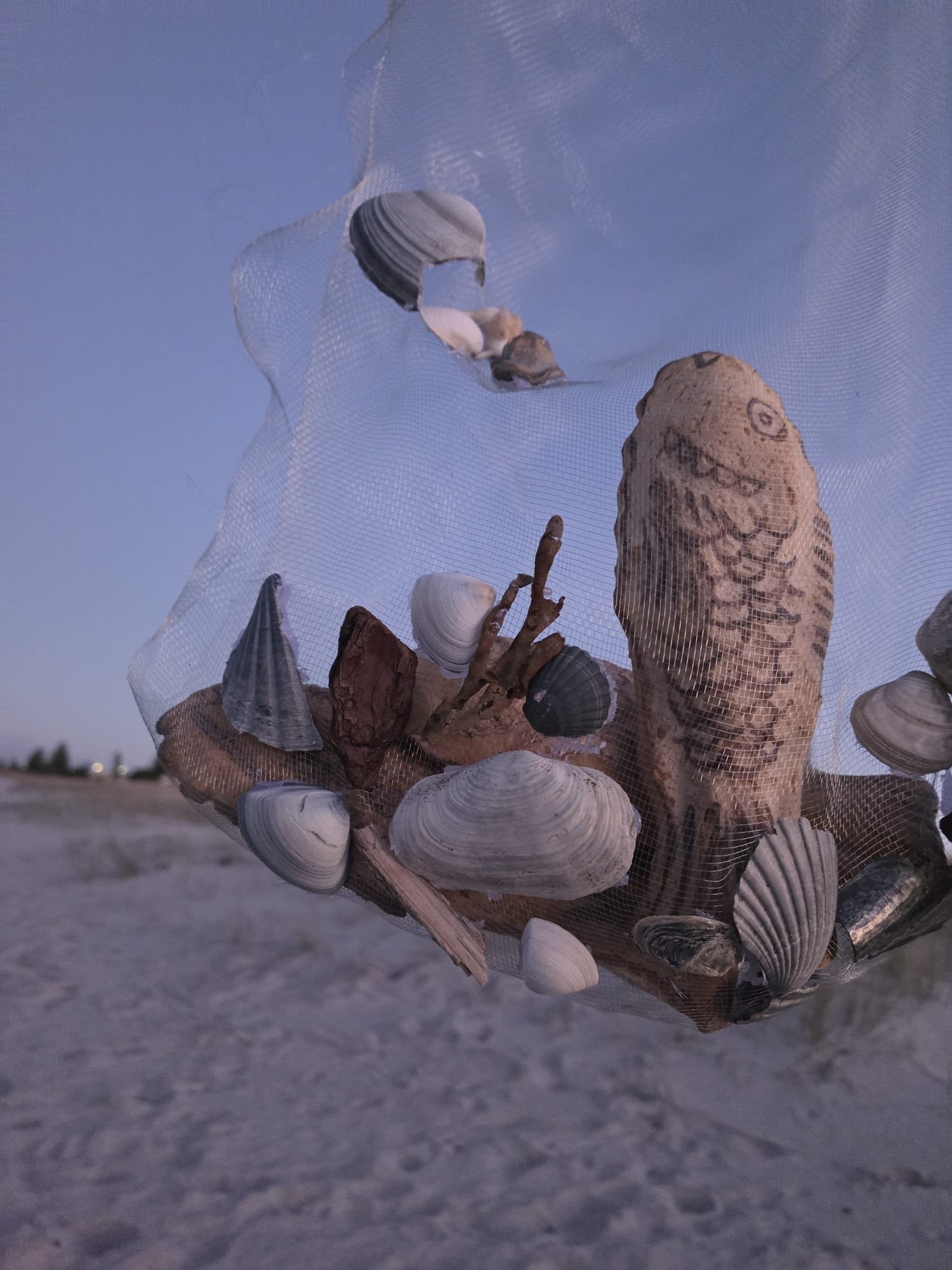 VECETO: Bread sculpture, net installation. A fish worked from dough rests among shells against a darkening sky.
