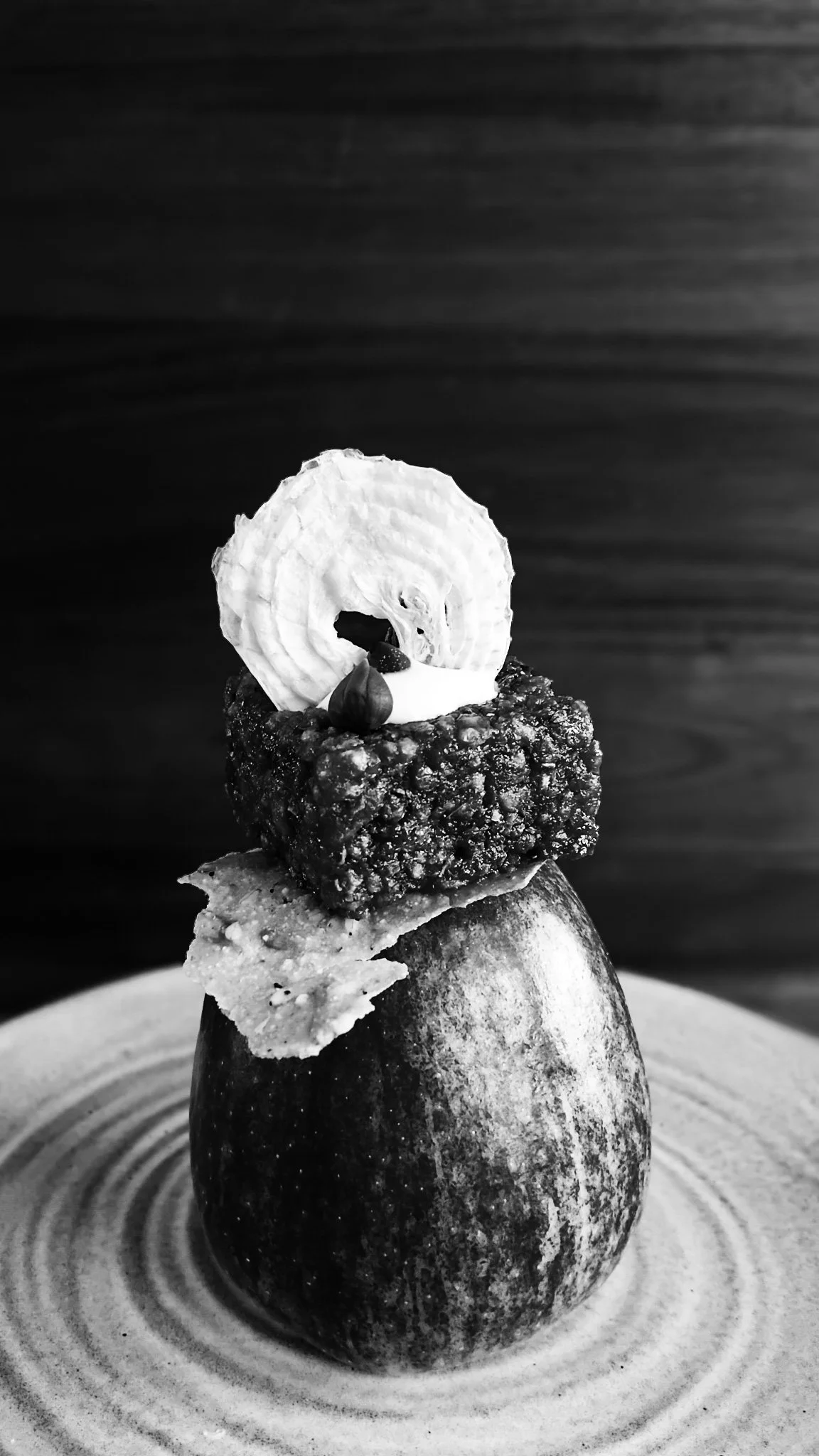 VECETO: Vertical stack on plate, dried onion ring standing. Culinary Architects articulate structural logic through monochromatic composition.