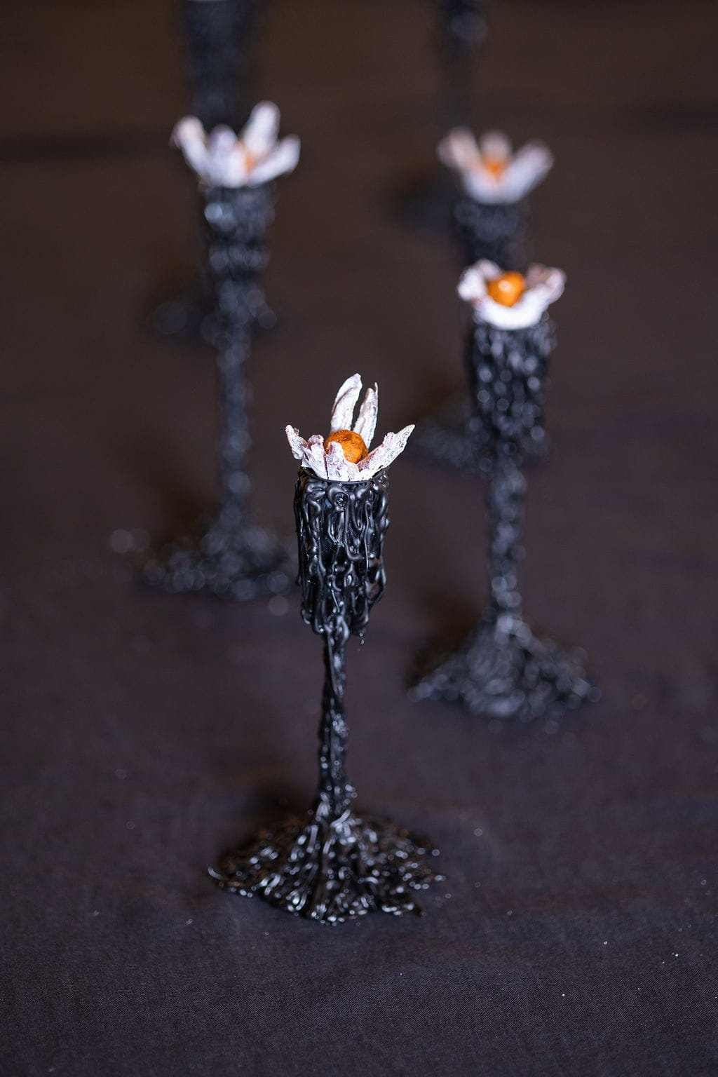 VECETO: Mycelium Cellar, candle holders and date flowers on black linen. Neoclassical order in orange and white.