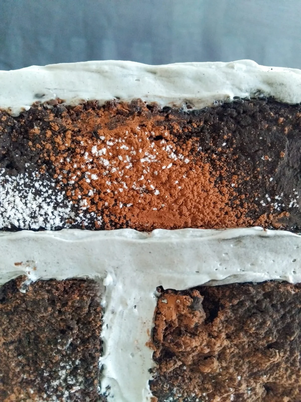Close-up mascarpone mortar between chocolate clinker layers, cacao powder surface, tactile materiality, edible architecture detail.