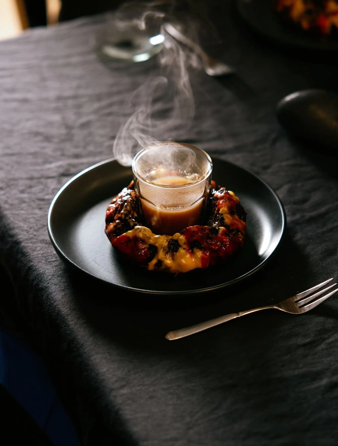Sensory installation by VECETO featuring a volcano cake releasing pine needle smoke from a glass.