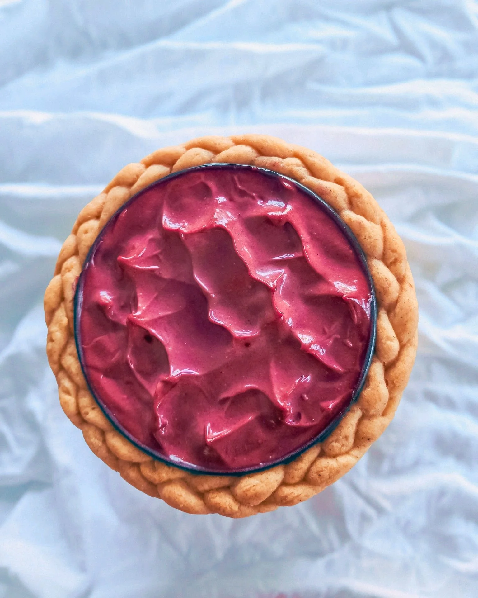 VECETO: Food still life, pink aioli pulled into peaks inside a braided bread wreath, seen from above.