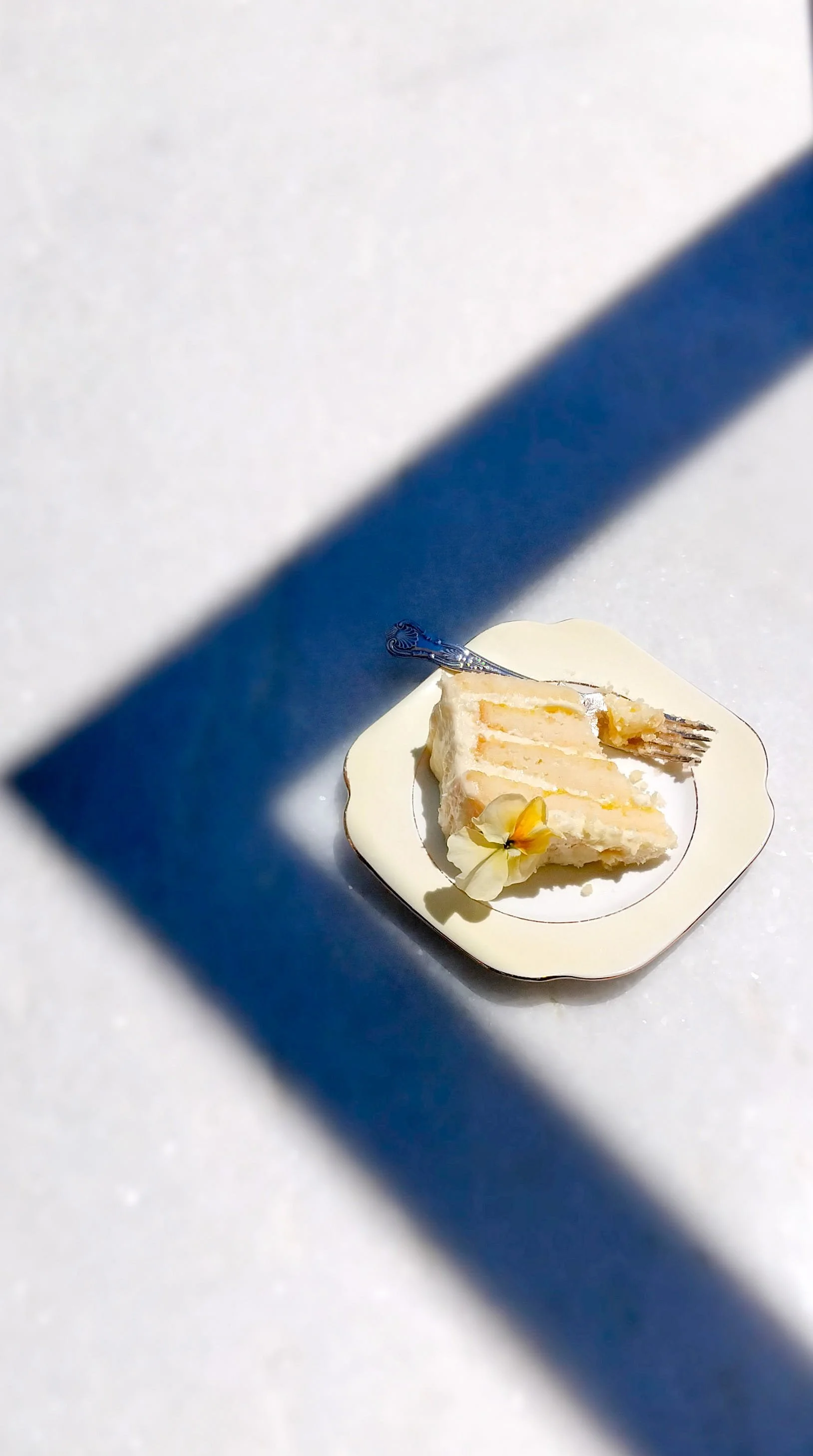 VECETO: Plate set at the corner of a window shadow on marble. Geometry deliberate, placement exact.