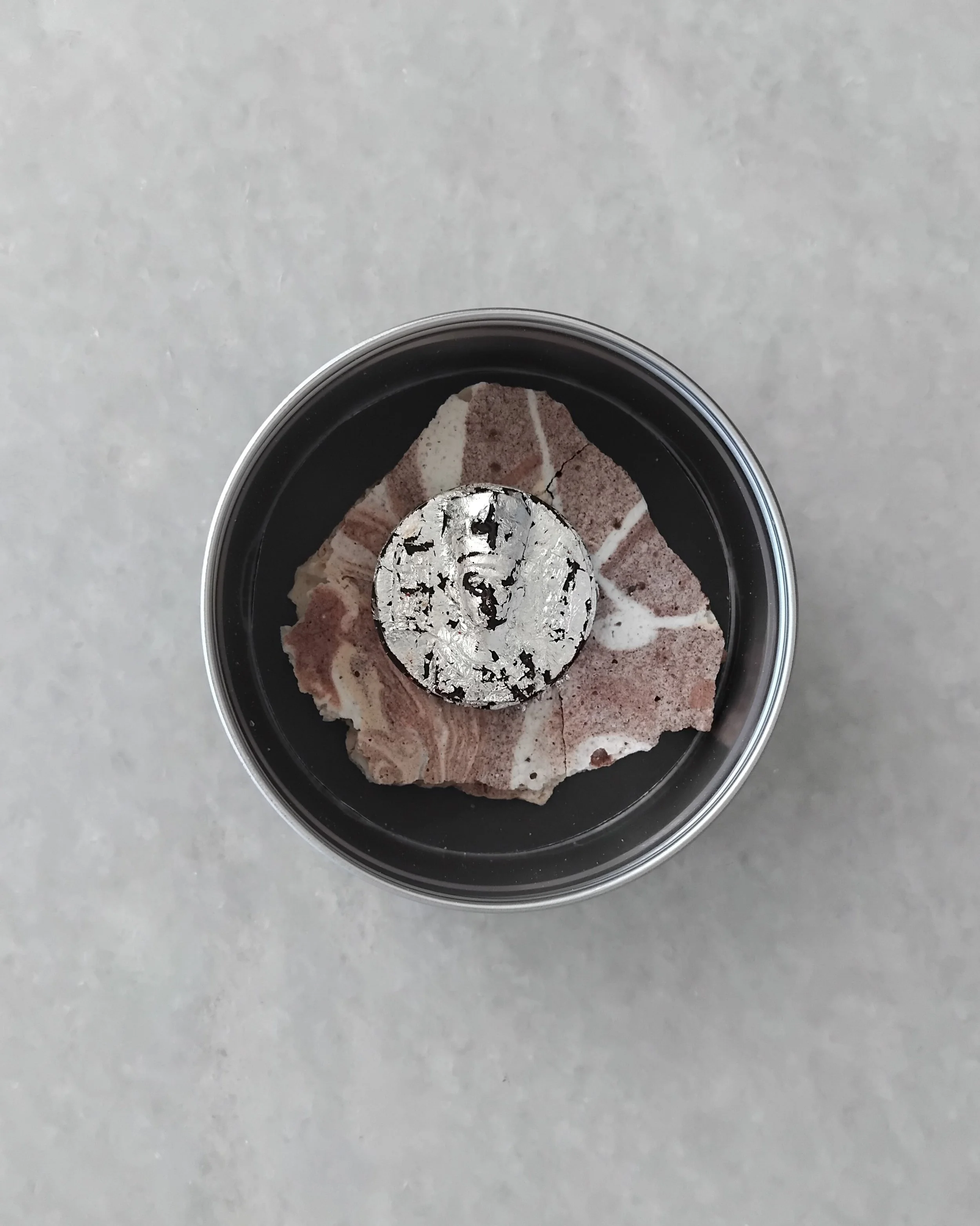 Silver on stone, pink beneath: boxed edible invitation with chocolate coin in edible silver leaf. VECETO 2026.