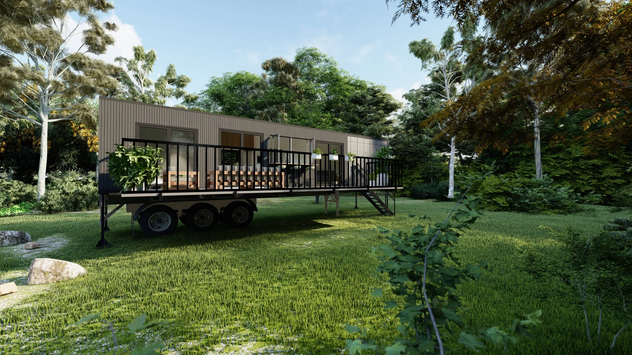 A tiny home on wheels with a deck, set in a lush, green forested area with trees and grass.