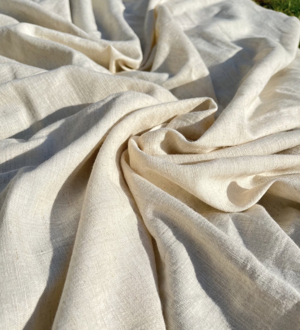 Close-up of beige or cream-colored fabric, slightly wrinkled and gathered in folds.