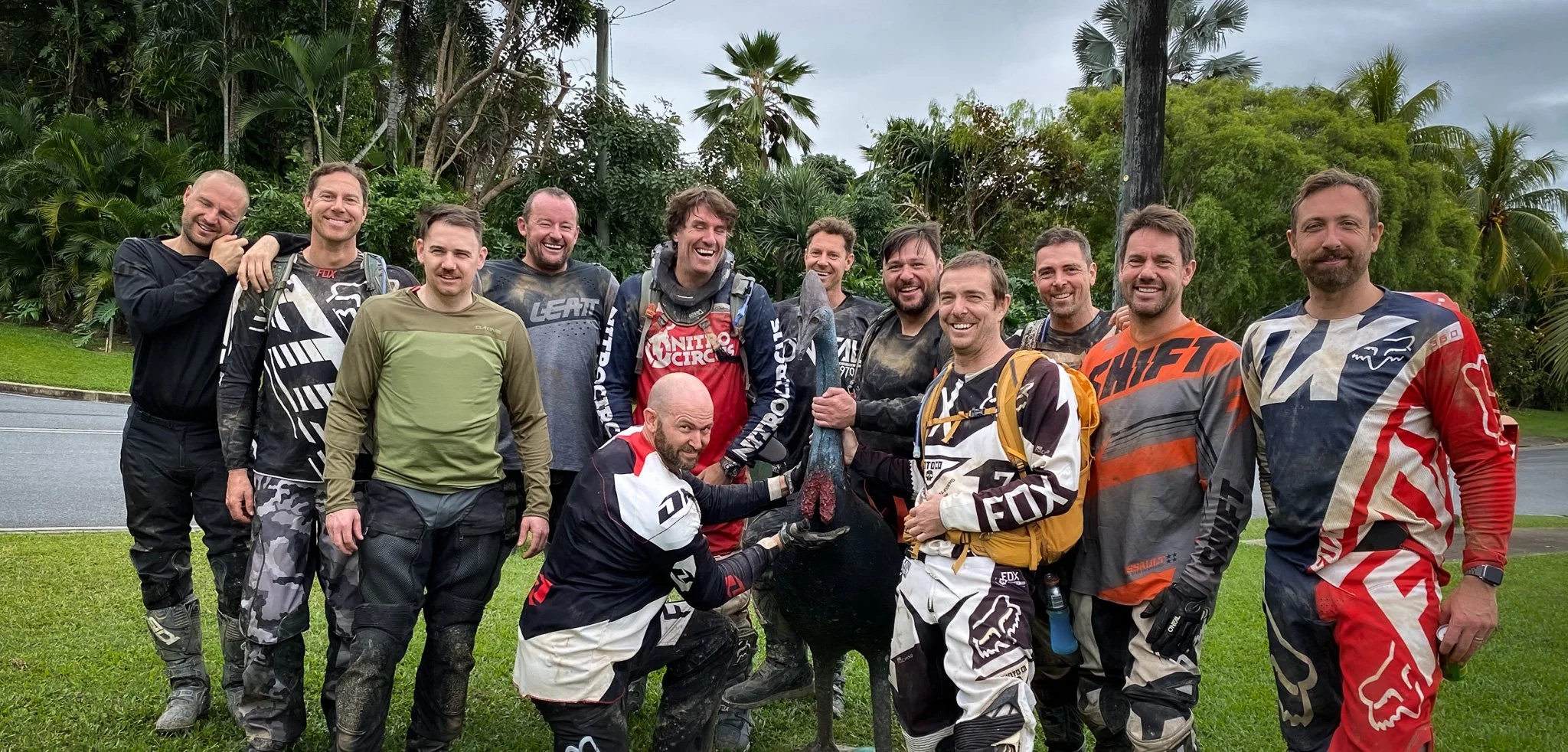Trail bike tour group celebrating after a ride in Cairns, popular for bucks party adventures and group motorcycle tours Group of mates on a Cairns motorcycle tour standing together after a day of off road riding in Far North Queensland.