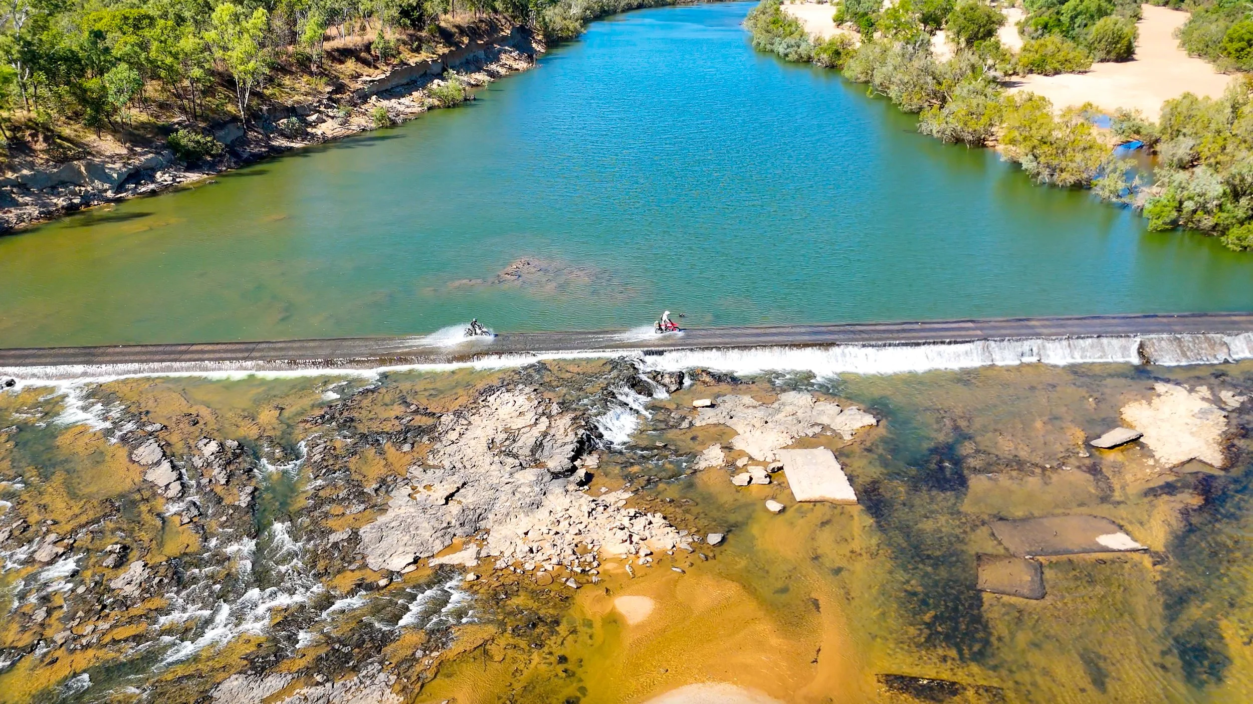 Riders crossing a river on a Cairns to Darwin motorcycle tour showcasing off-road water crossings in the Australian outback