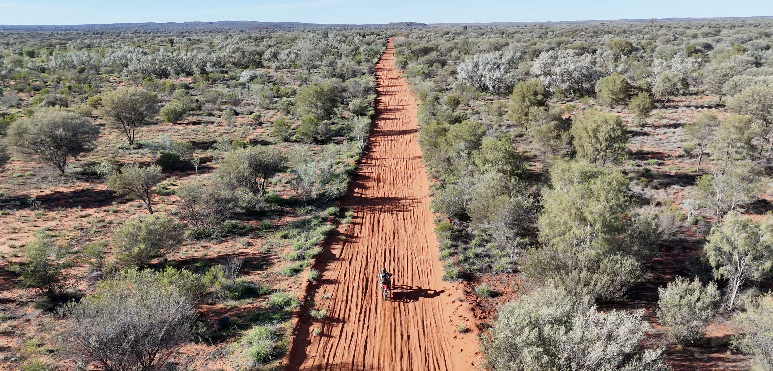 Aerial view of a dirt bike riding the Finke Track showcasing deep sand and remote outback terrain Off-road motorcycle riding along the famous Finke Track in central Australia on a desert adventure tour
