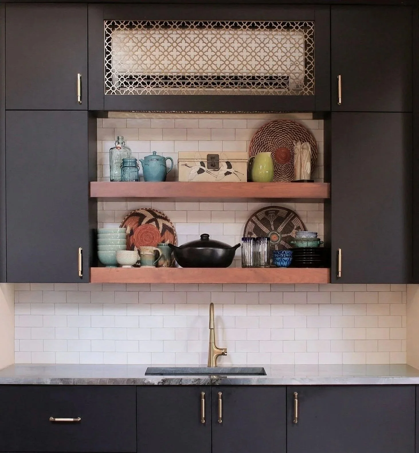 Open kitchen shelving styled with artisan ceramics, woven baskets, natural textures, and collected decor in an organic modern interior.