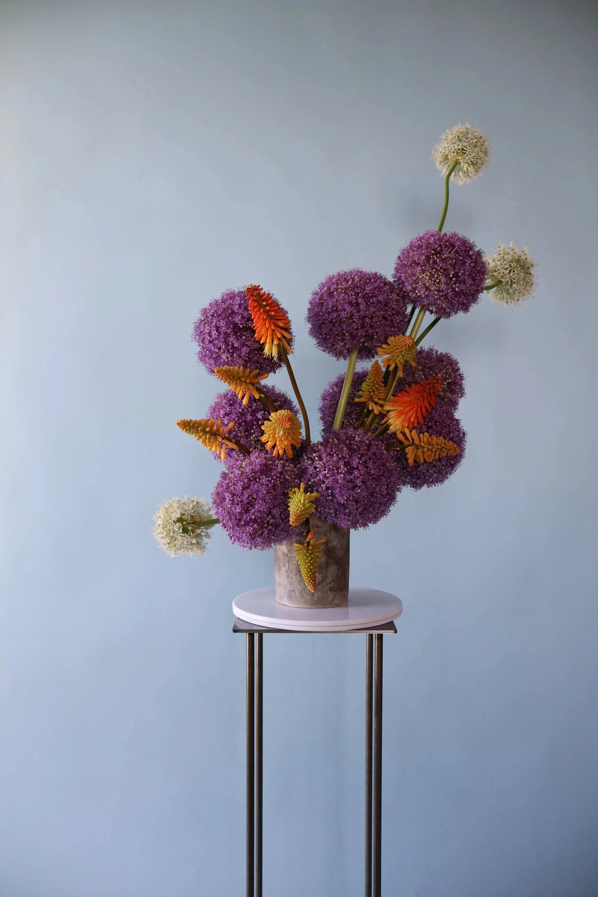 Colorful flower arrangement with orange, pink, and yellow blooms in a white vase.
