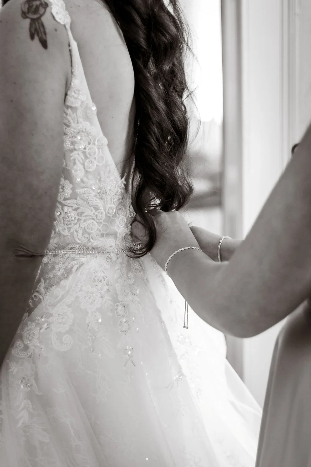 Black and white photo of daughter doing up mother's wedding dress on wedding day in Richmond Tasmania. Captured by Amy Lyon Creative