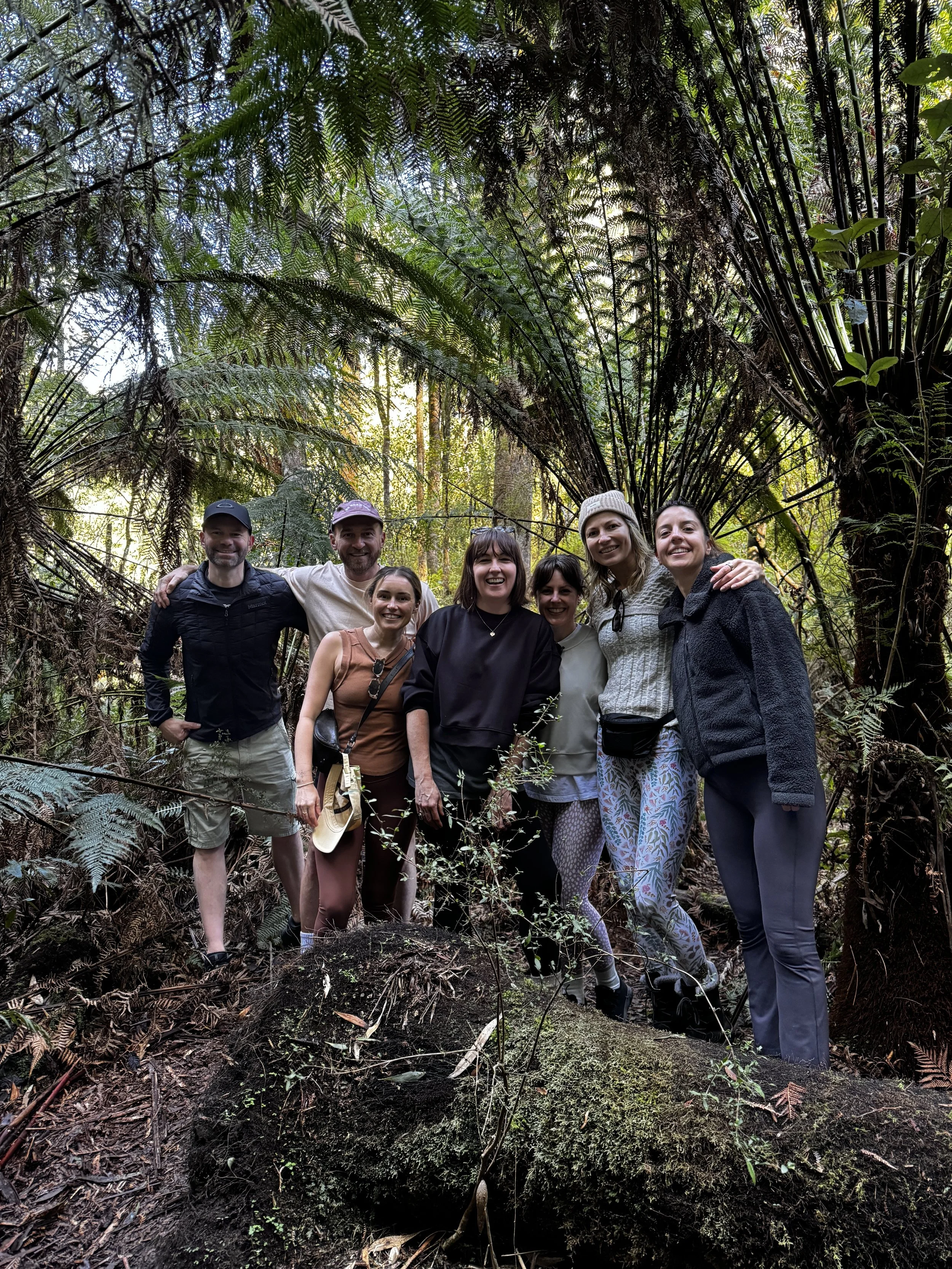 Group of people posing in a forest with tall ferns and lush greenery, the beautiful countryside being discovered on a Yoga and Meditation retreat in The Otways
