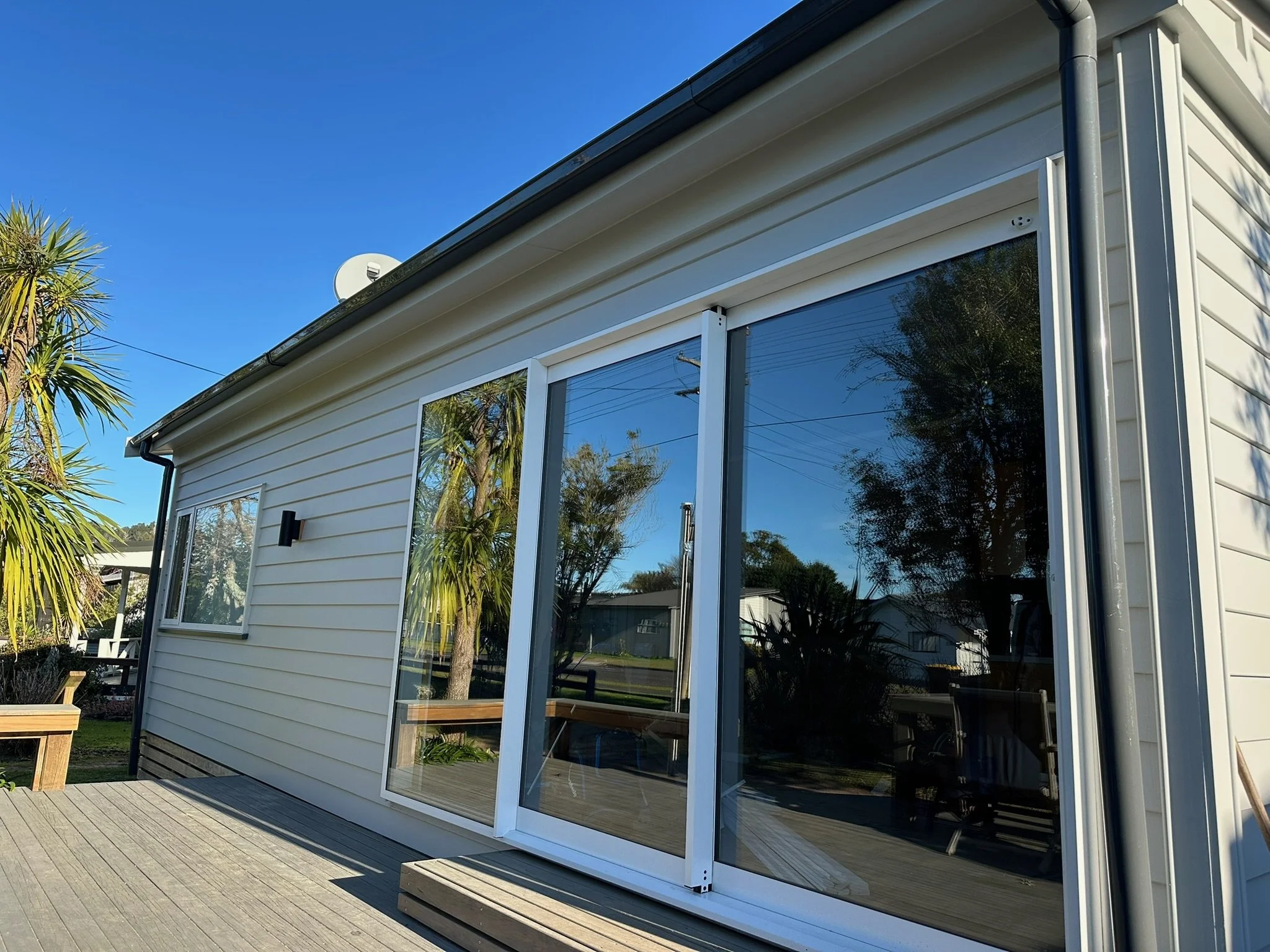 The image shows a house with large glass sliding door leading to a wooden deck