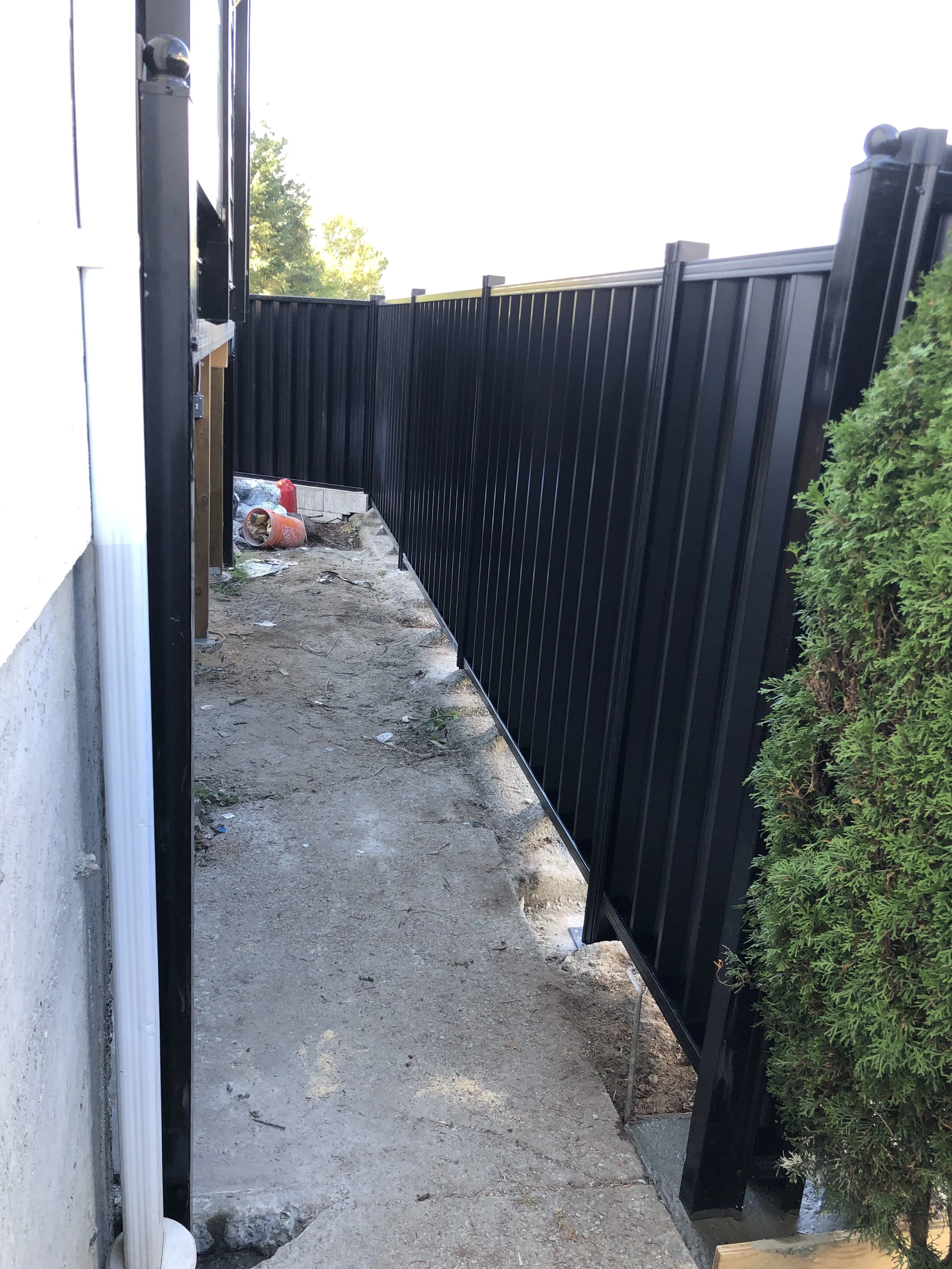 narrow outdoor alley with black metal fence and concrete ground
