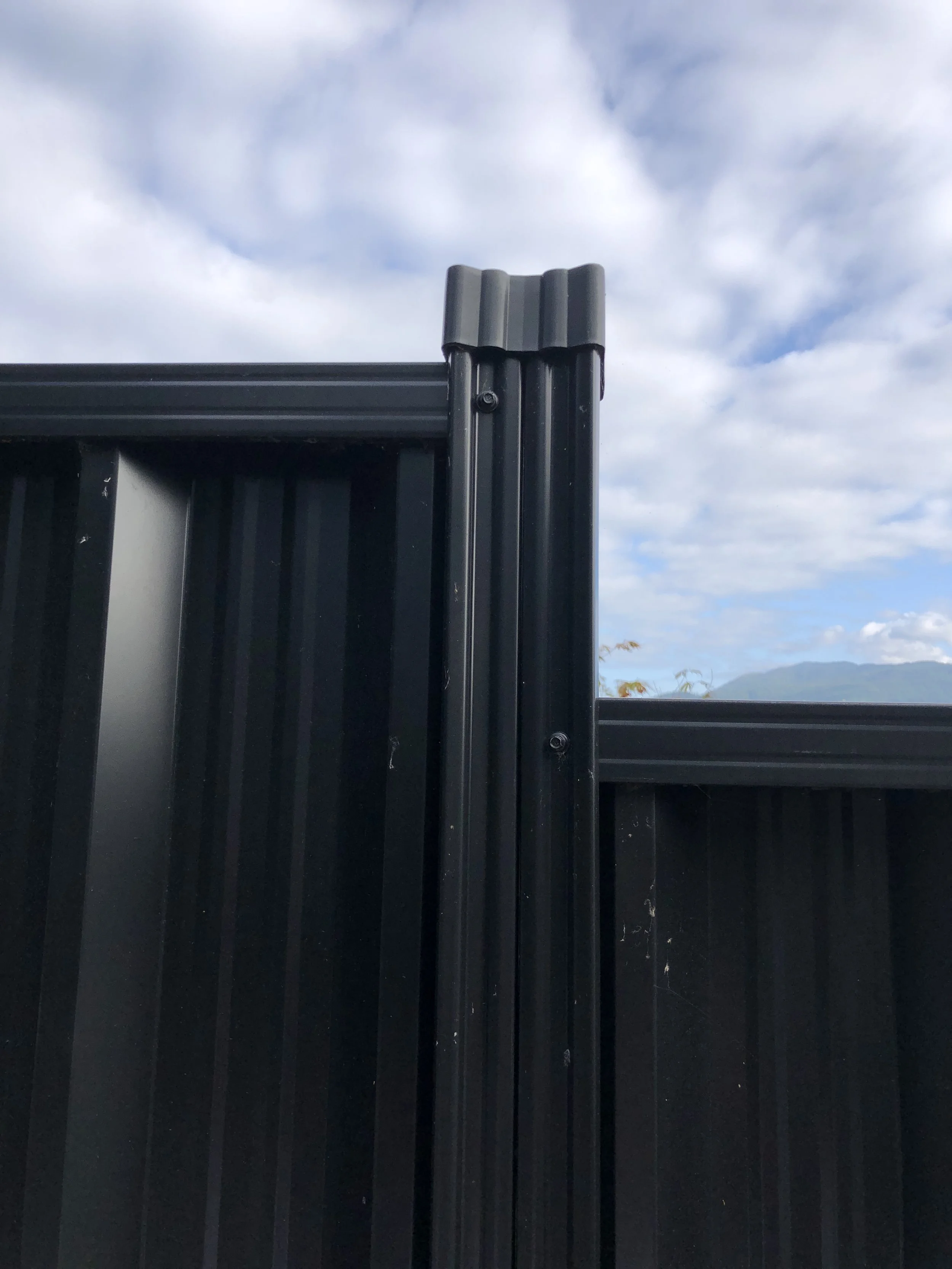 Black metal fence with a cloudy sky background.
