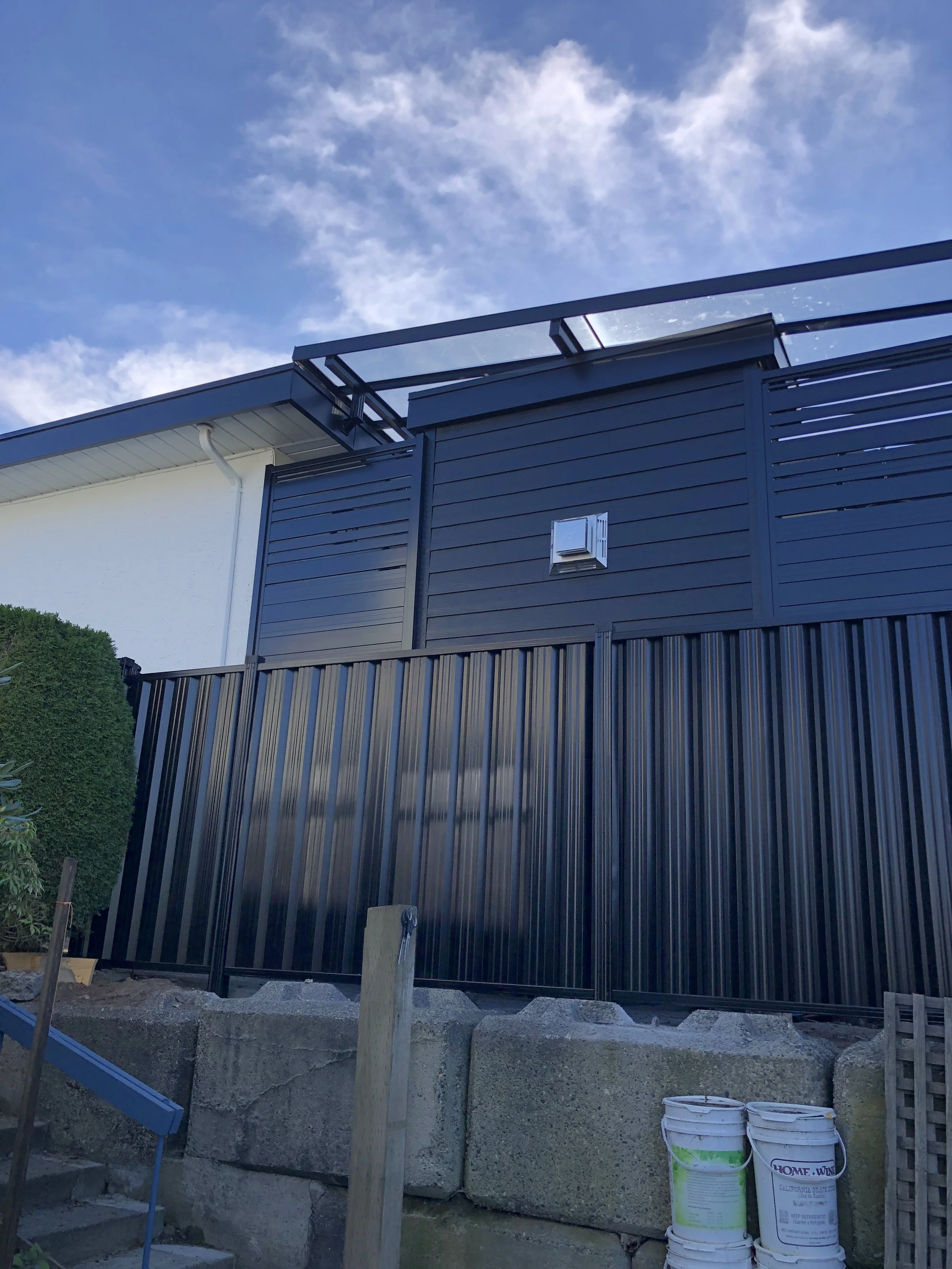 Modern black metal fence with concrete base and clear sky