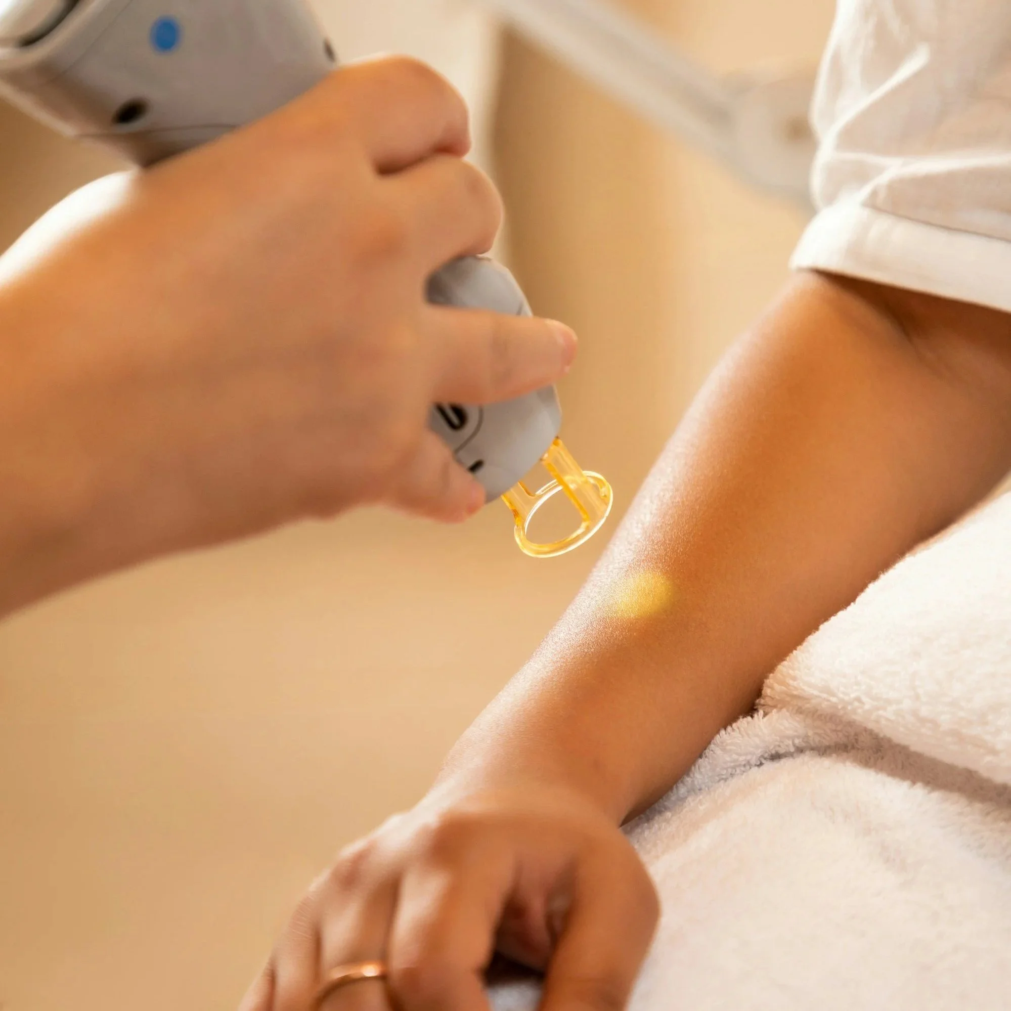 A person holding a medical device near their arm, likely preparing for a blood draw or injection, with a cloth or towel underneath.