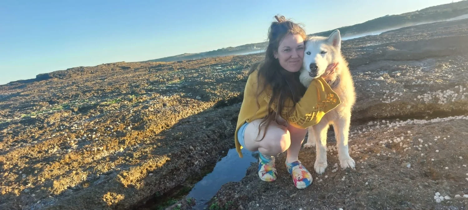 Shana with a husky on a rocky coastline