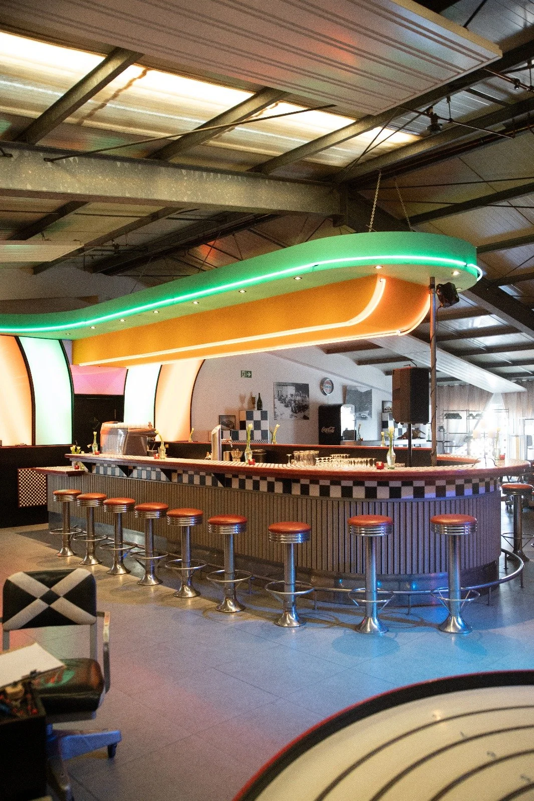 Innenaufnahme einer Bar mit bunter, neonbeleuchteter Decke und Barhockern.