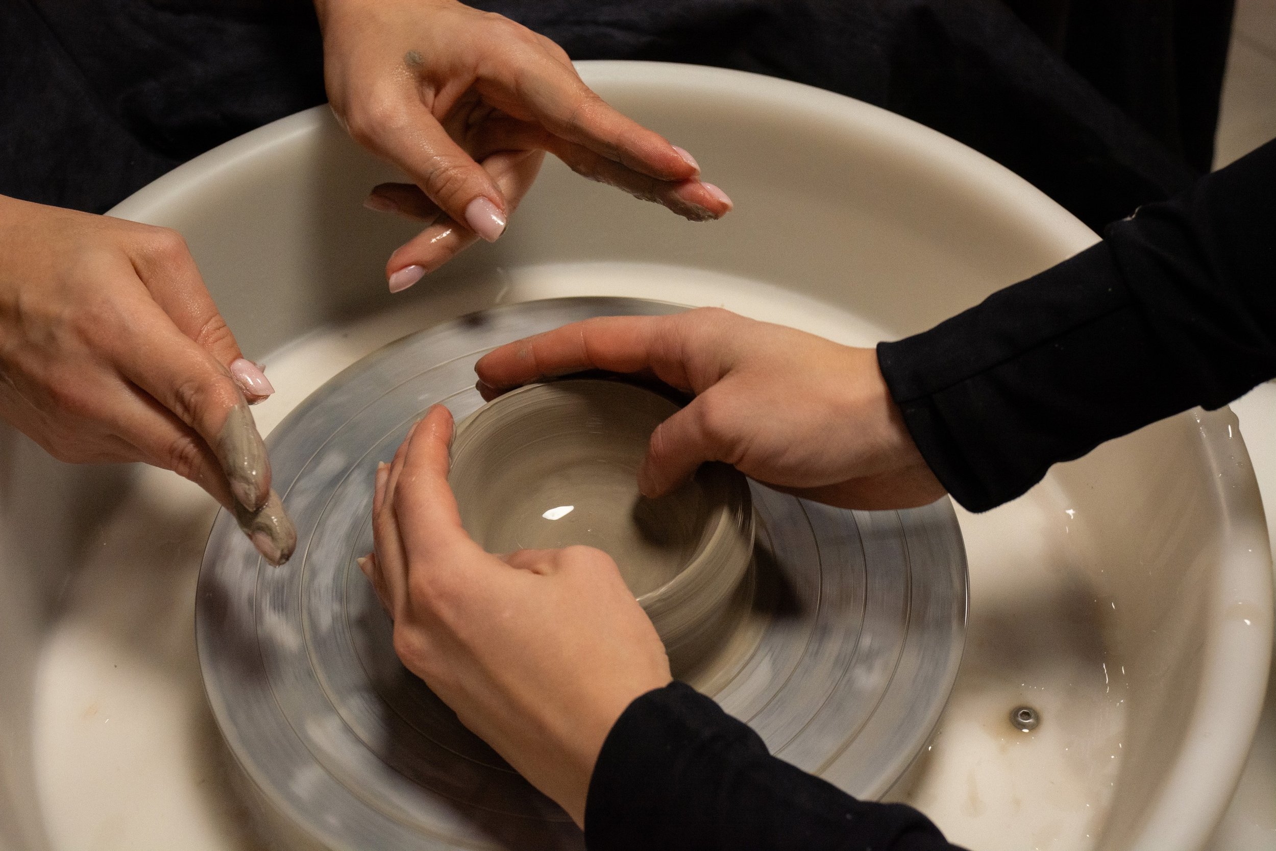 Pottery classes Munger Place beginner shaping clay on a pottery wheel