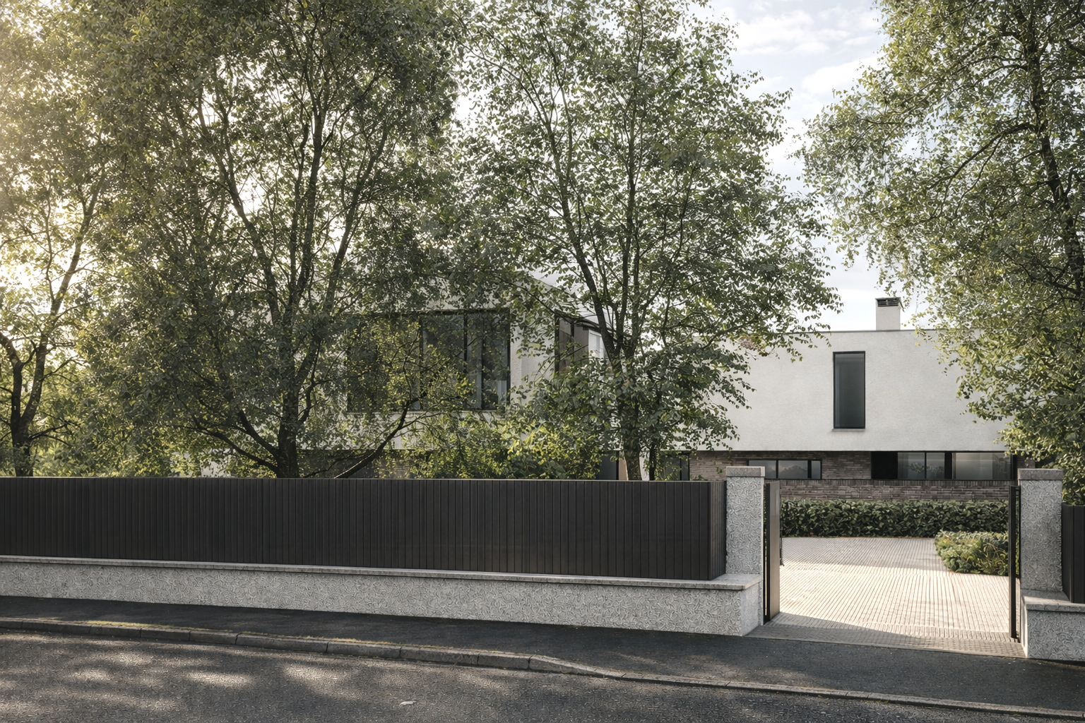 Modern white house behind black fence and trees, with a paved driveway and a pathway to the entrance.