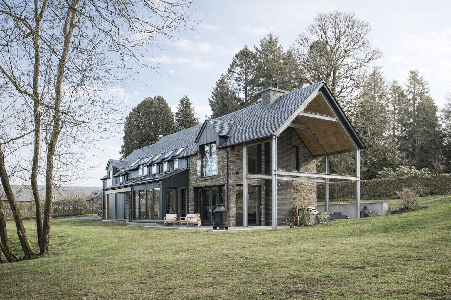 Modern house with brick and black exterior, large windows, and a sloped roof, set in a grassy yard with trees in the background.