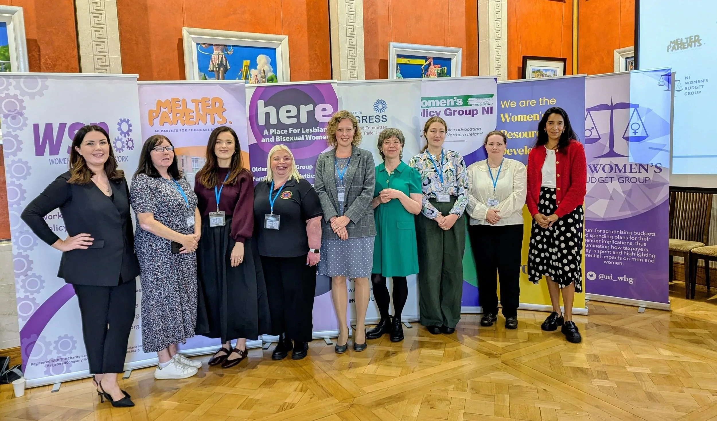 A group of women standing in front of roll up banners.