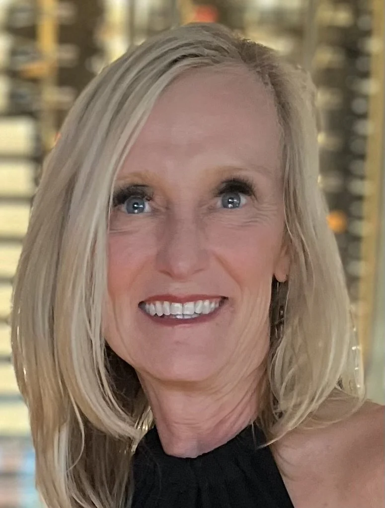 Kelly Miller is a white woman with shoulder-length blonde hair, blue eyes, and a black tank top, smiling at the camera