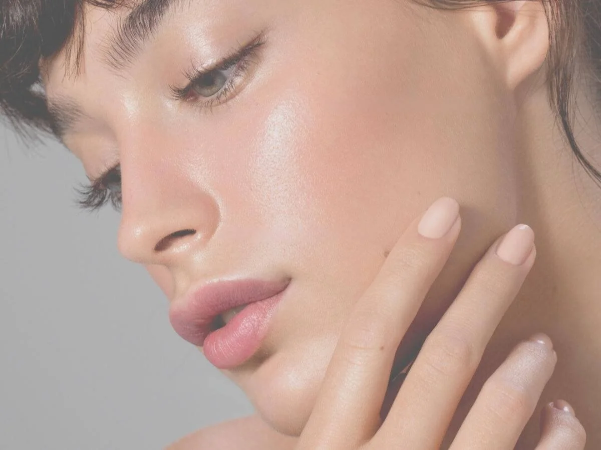 Image of a beautiful young woman's side face showing her smooth skin, pointed nose, almond eyes and pouty lips