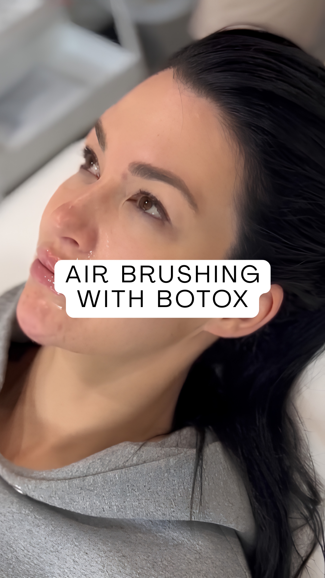 A woman lying down receiving air brushing with Botox on her face.