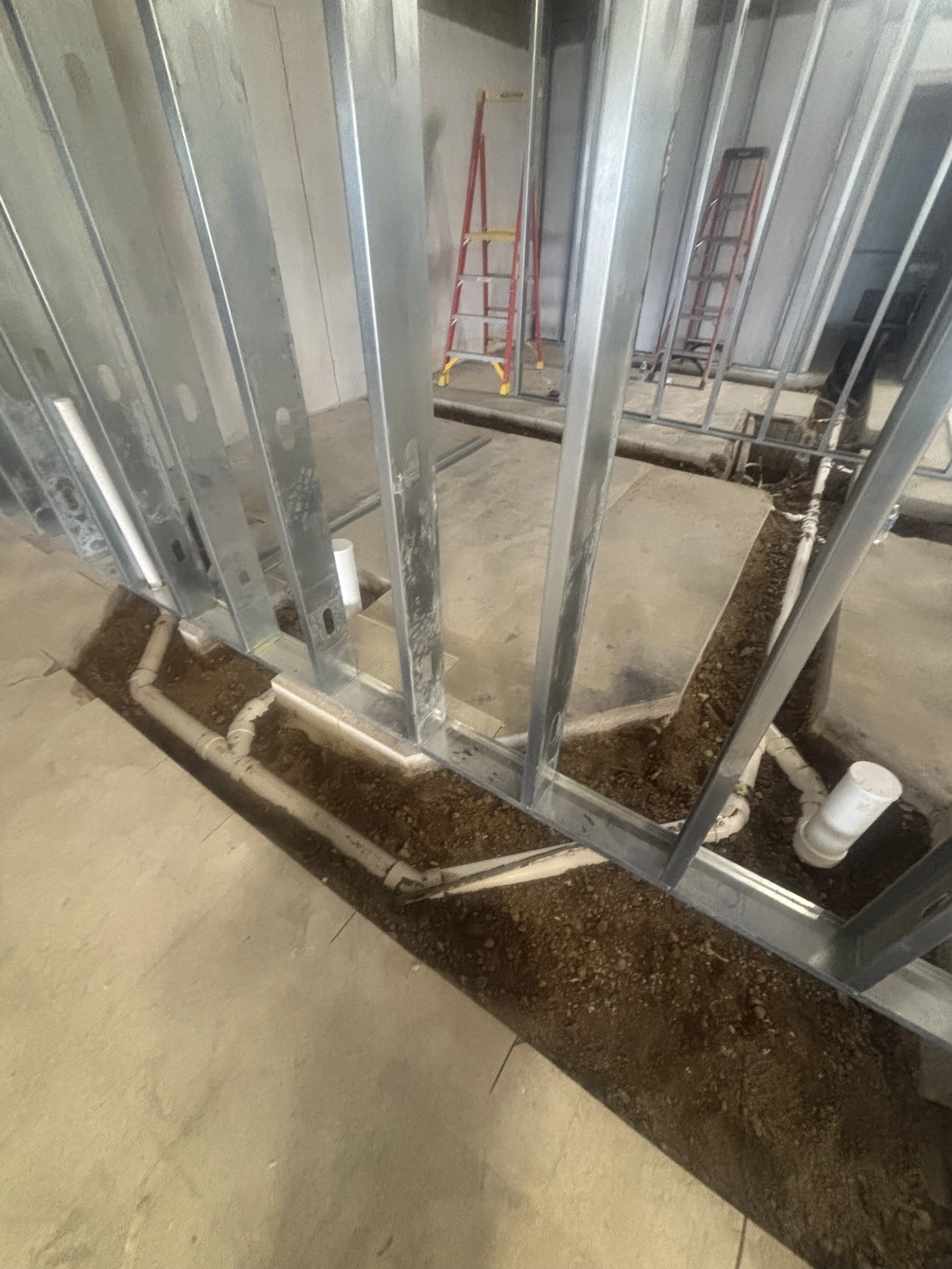 Commercial plumbing rough-in installed inside framed walls during construction