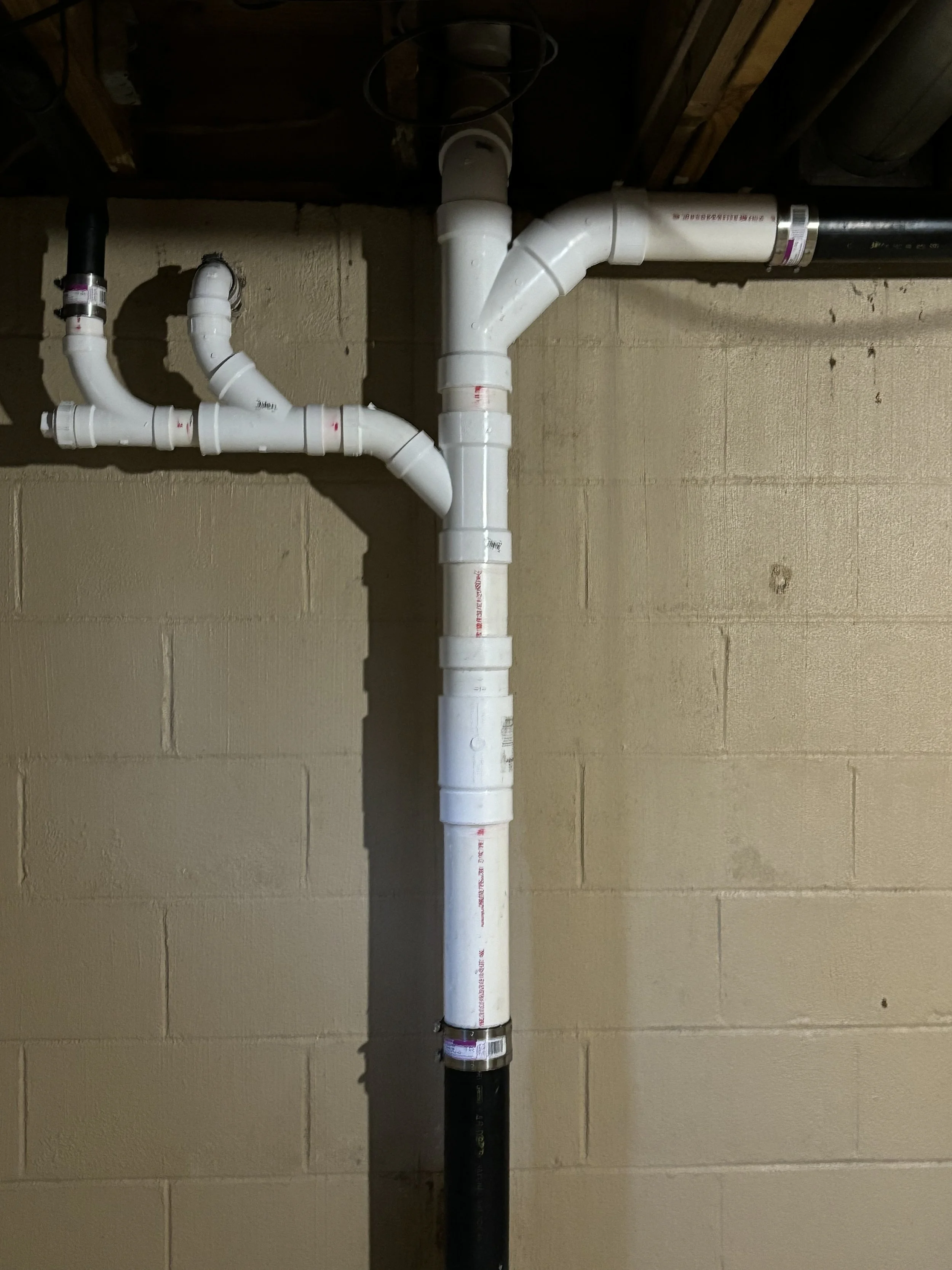 Drain stack replacement by RonJon Plumbing in Delaware, Ohio, featuring new PVC piping, three-inch main line, toilet flange, and expansion fitting installed in place of old ABS plumbing.