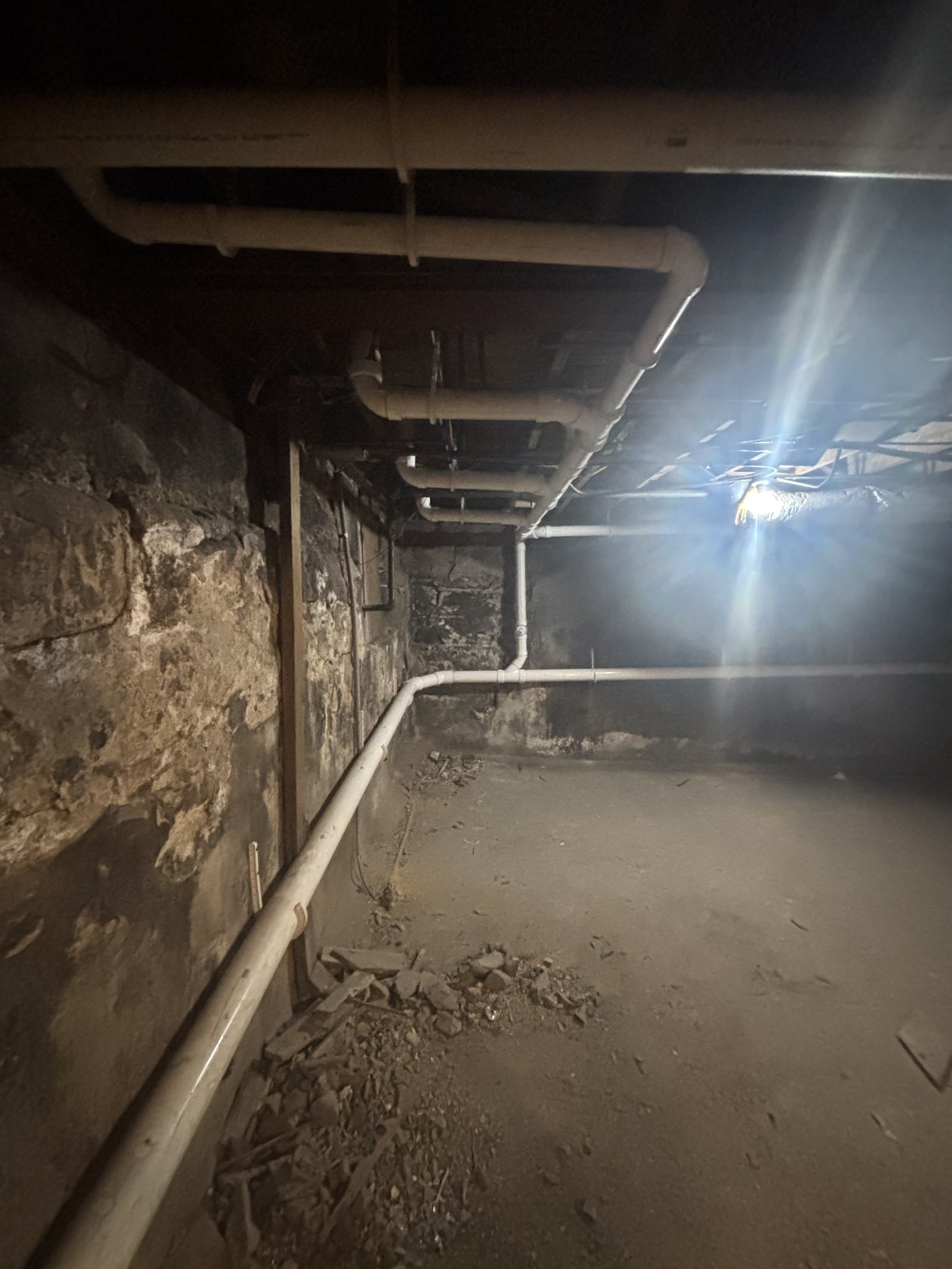 Commercial bathroom rough-in plumbing by RonJon Plumbing in Columbus, Ohio, showing three toilet drains, lavatory rough-in, and a four-inch main stack along the basement wall.