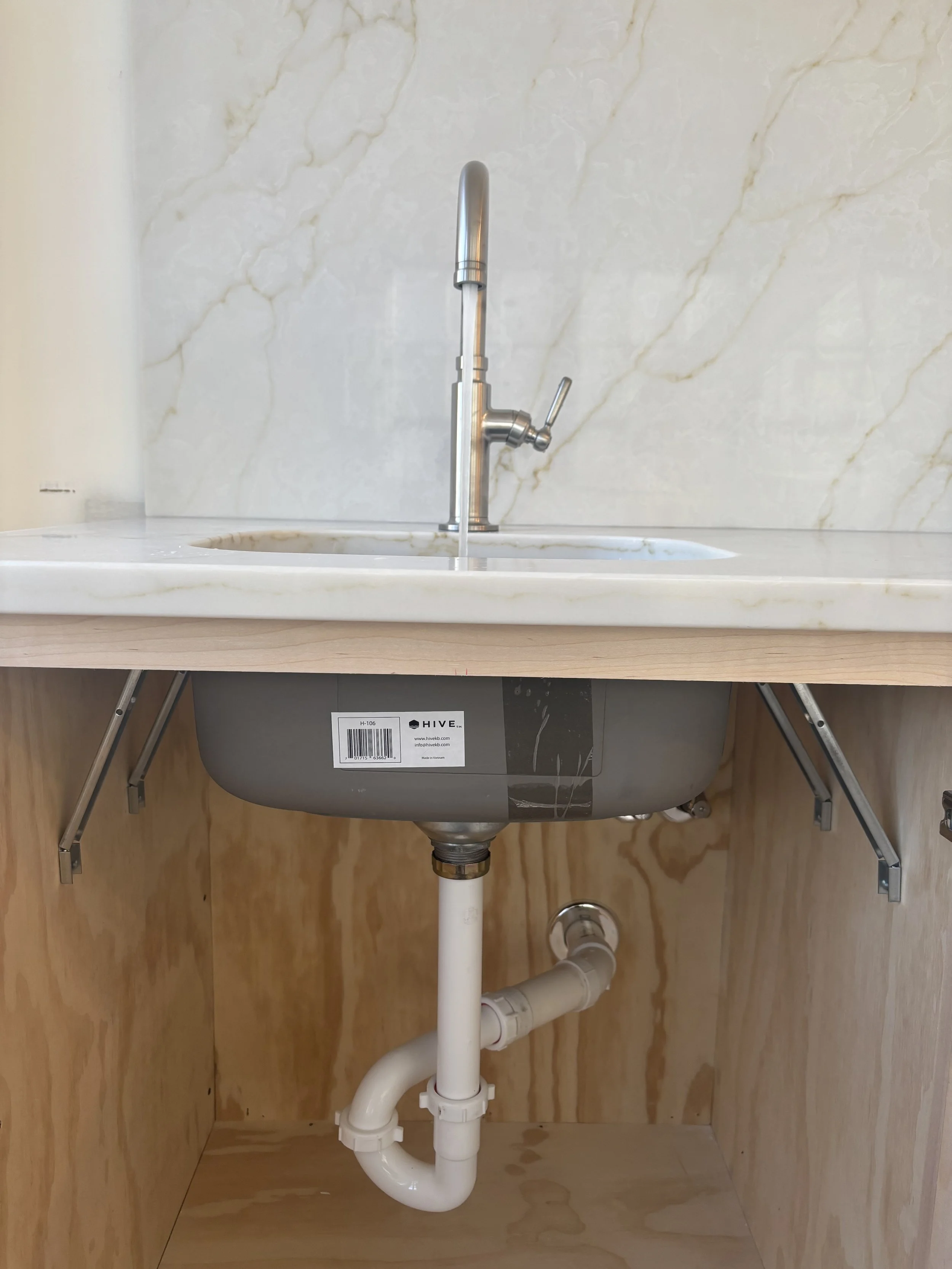 New sink and faucet installation by RonJon Plumbing in Powell, Ohio, featuring new tubular drain piping, chrome shutoff valves, and supply lines neatly connected under the vanity.