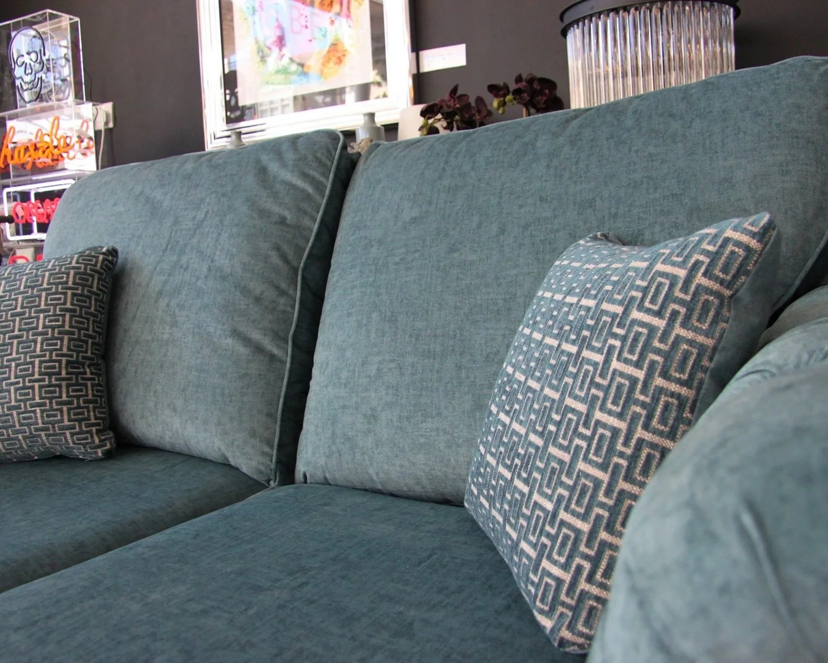 A teal sofa with patterned cushions in a home or showroom setting.