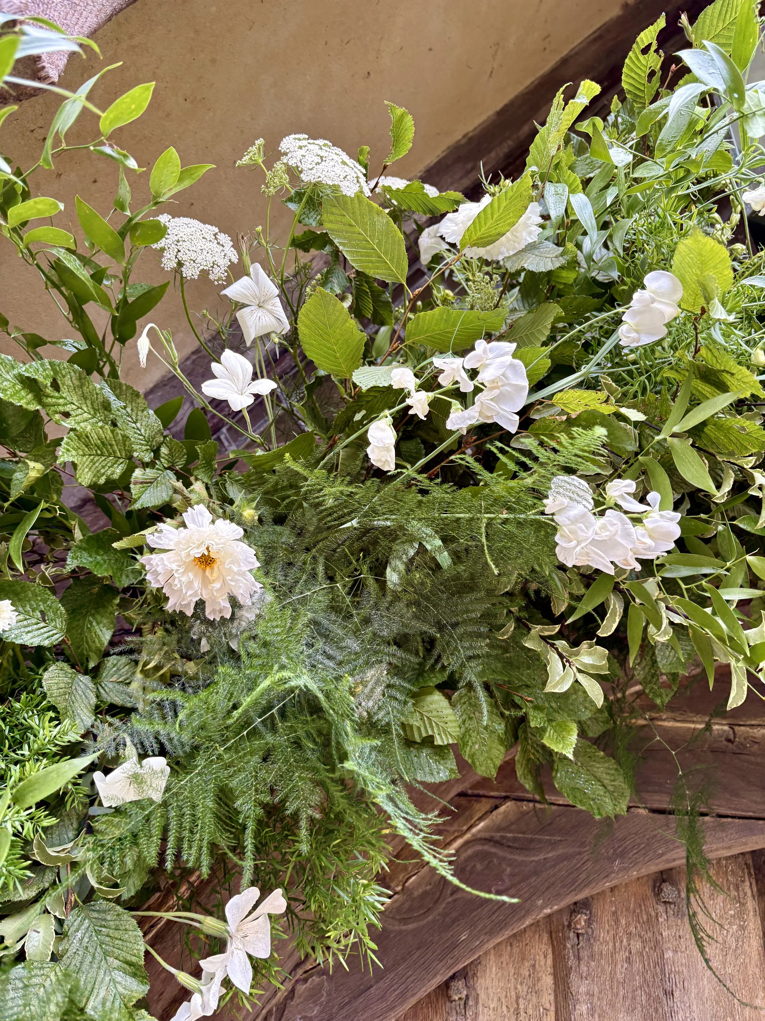 A collection of white flowers and green foliage created over a church entrance arch.