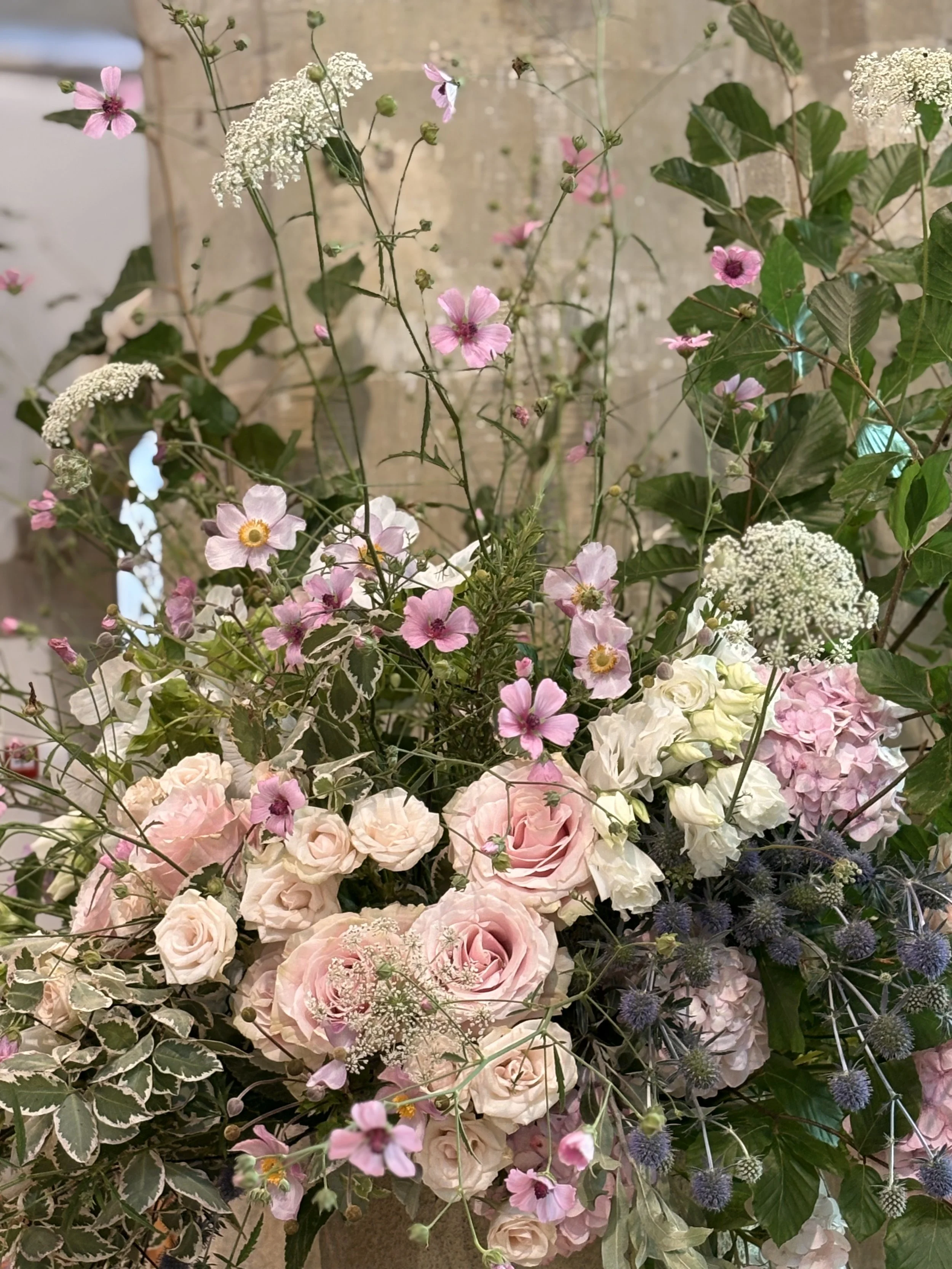 A bouquet of pink and white flowers including roses, hydrangeas, and smaller blossoms with green foliage.