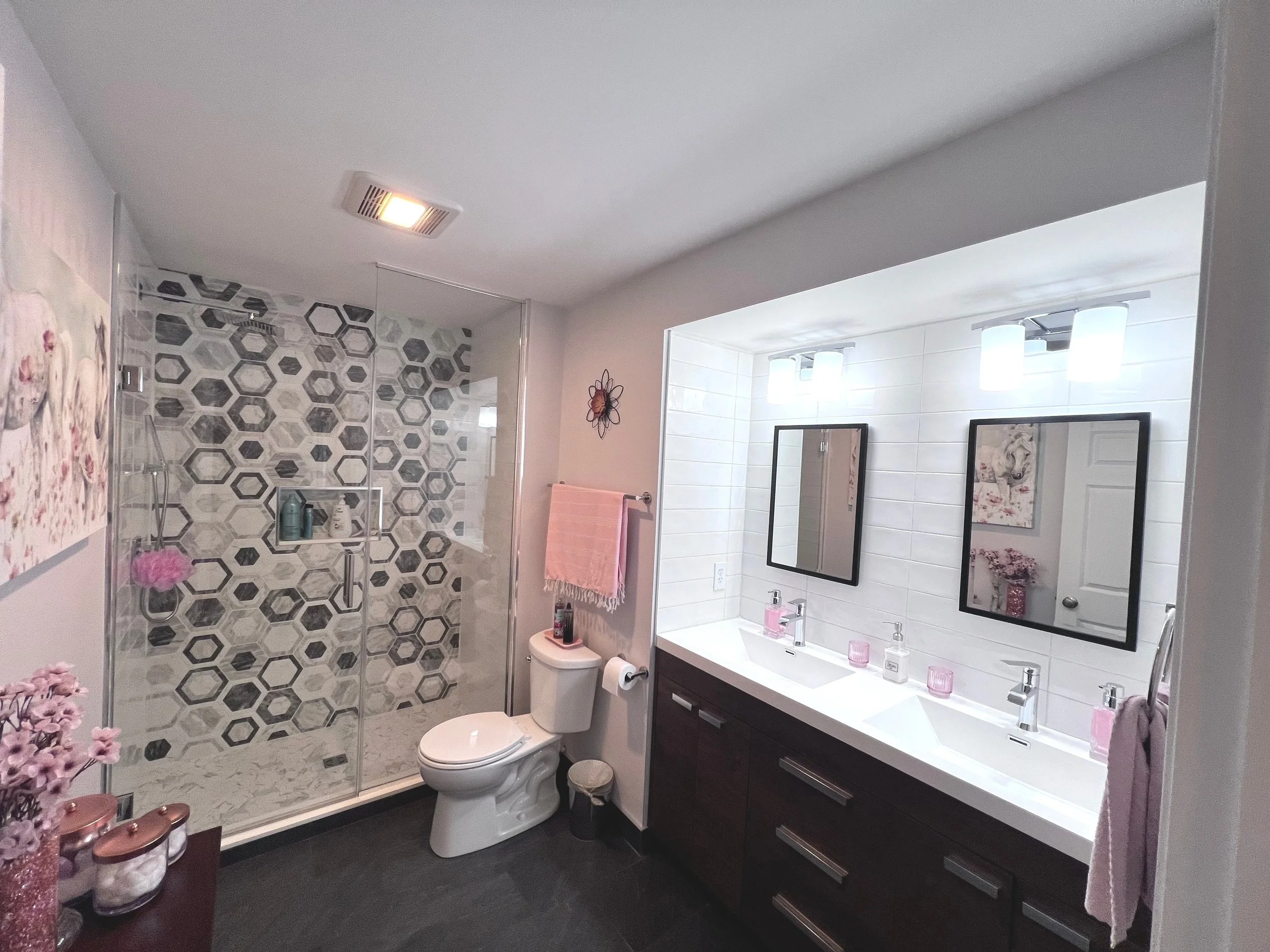 Modern bathroom with double vanity, large mirrors, and a walk-in shower with hexagonal tile design.