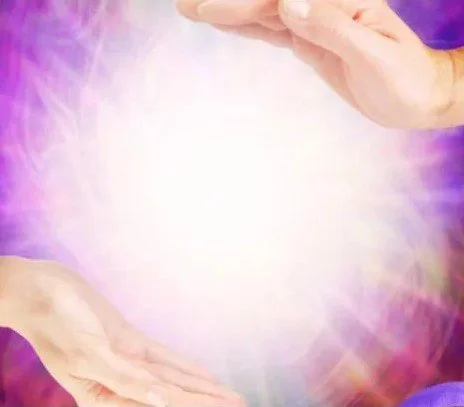 Two hands, one above and one below, with a bright light and colorful glowing background in purple and pink hues.