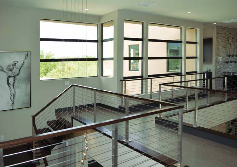 Modern interior of a building with a staircase, large windows, and artwork on the wall.