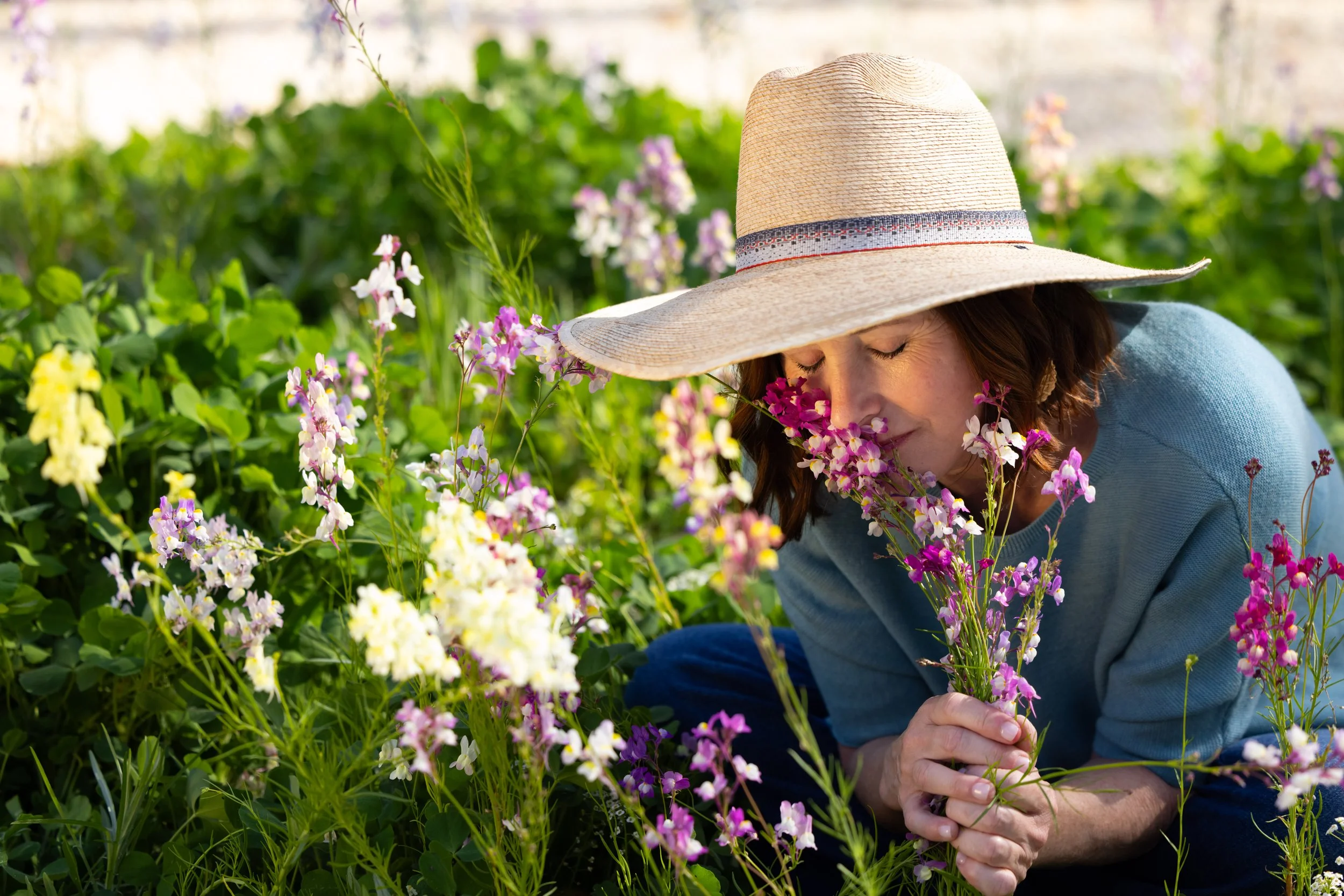 Ann Zalla standing in a Charleston garden surrounded by seasonal greenery and flowers.
