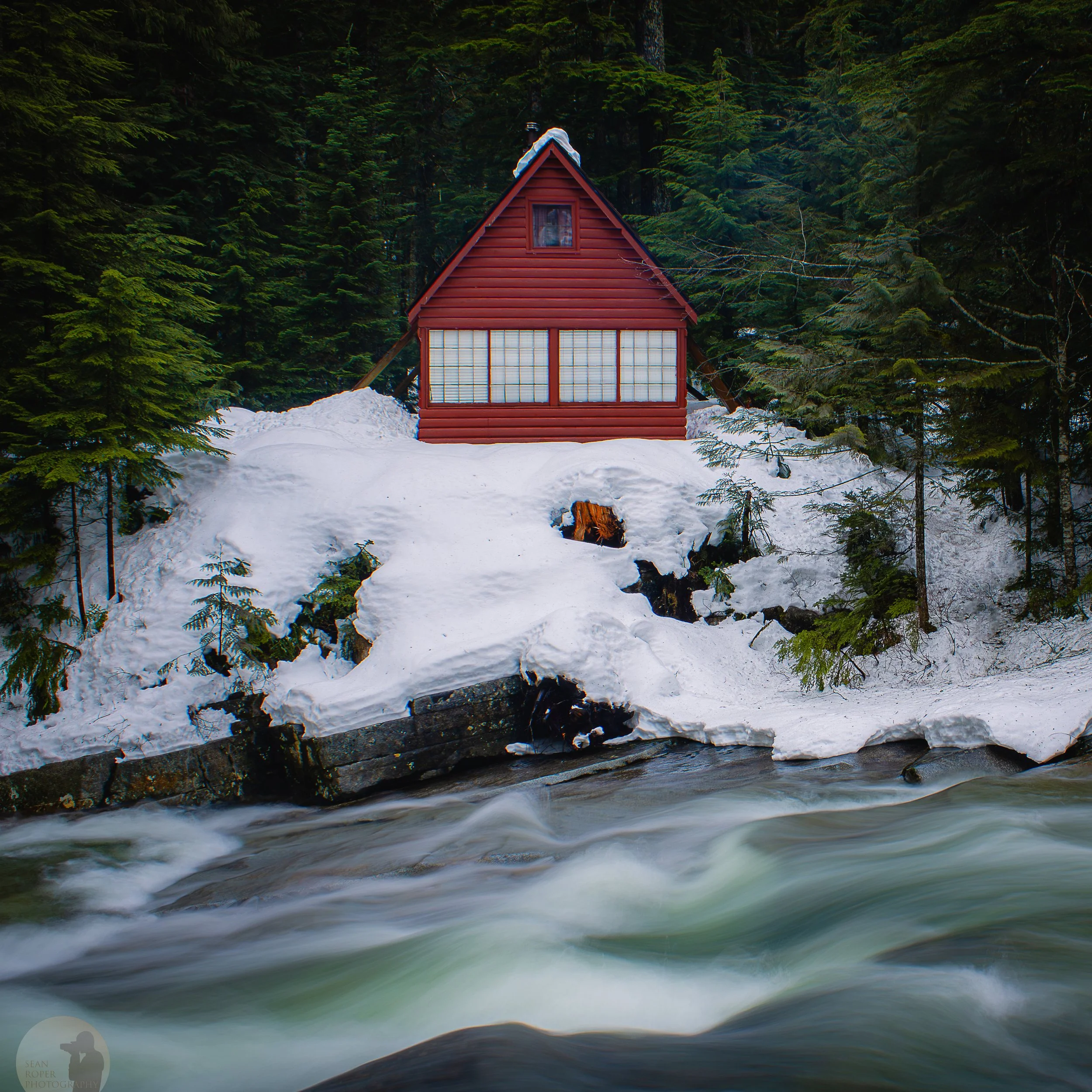 A cabin alongside the Snoqualmie river in winter.
