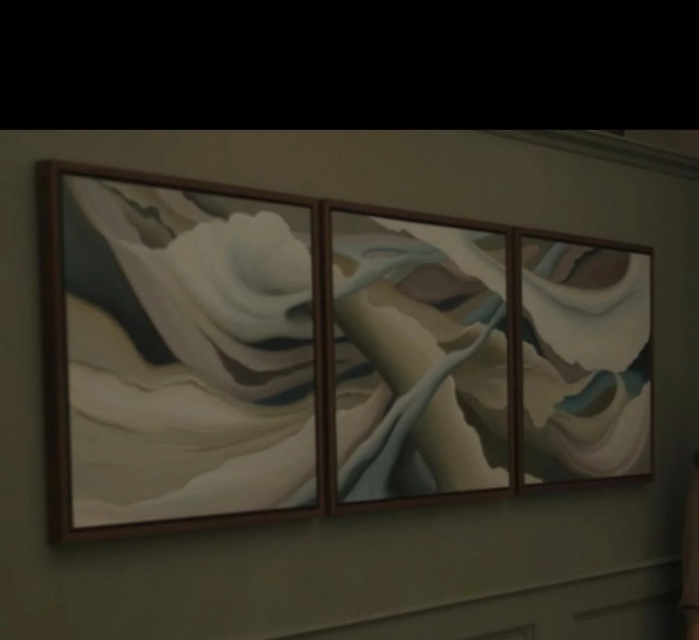 Triptych abstract painting with flowing, swirling patterns in beige, white, brown, gray, and light blue hues hanging on a wall.