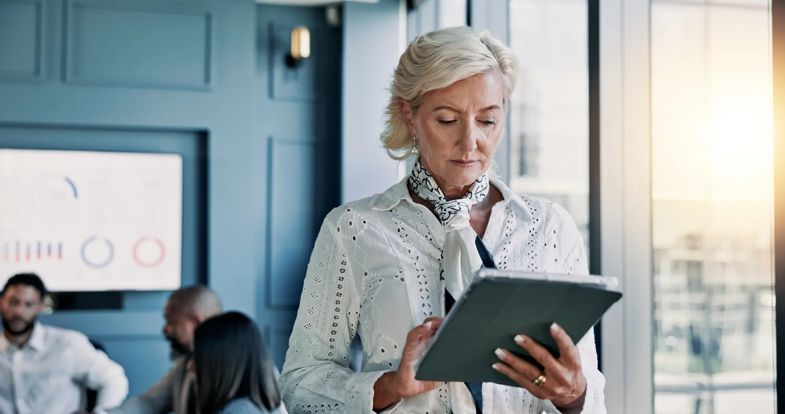 Female executive reviewing schedule on tablet in modern office, symbolizing time pressure and inefficient traditional healthcare